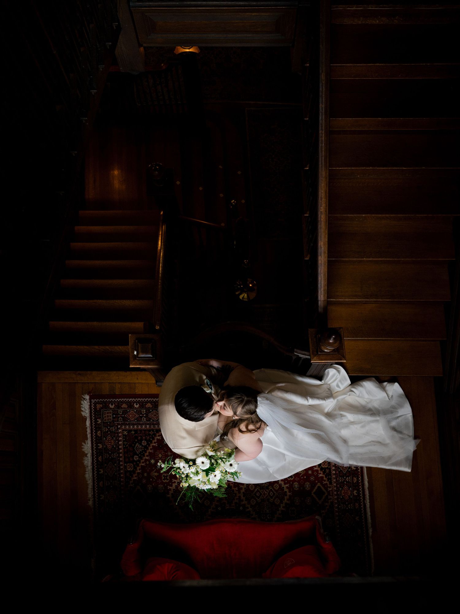 Aerial view of bride and groom kissing on an ornate rug at the staircase during their wedding at Historic Martin Mansion in Virginia.