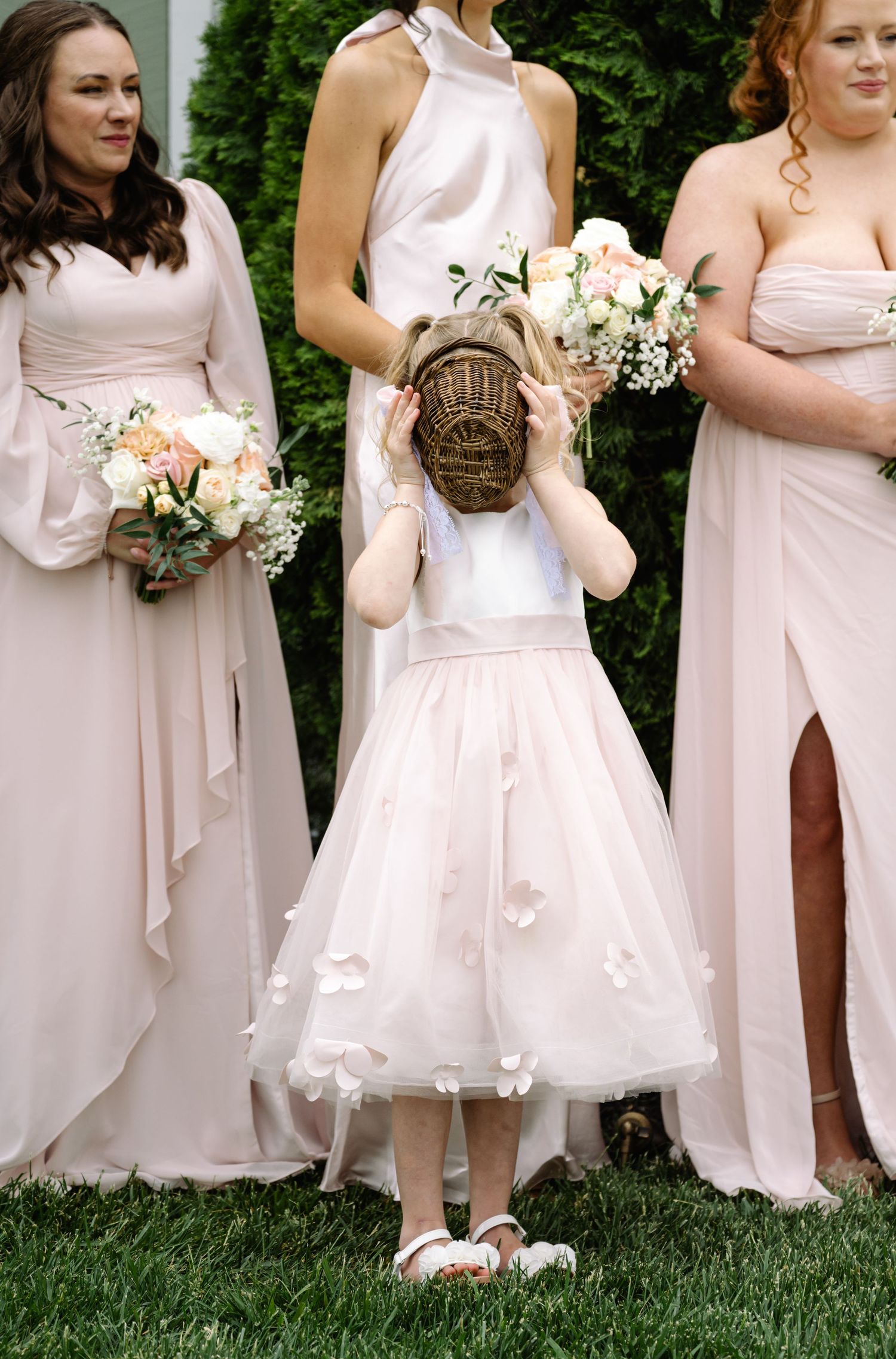 Flower girl in blush tulle dress beside bridesmaids in pink gowns at The Barns at Timberneck Wedding Venue in Smithfield Virginia.