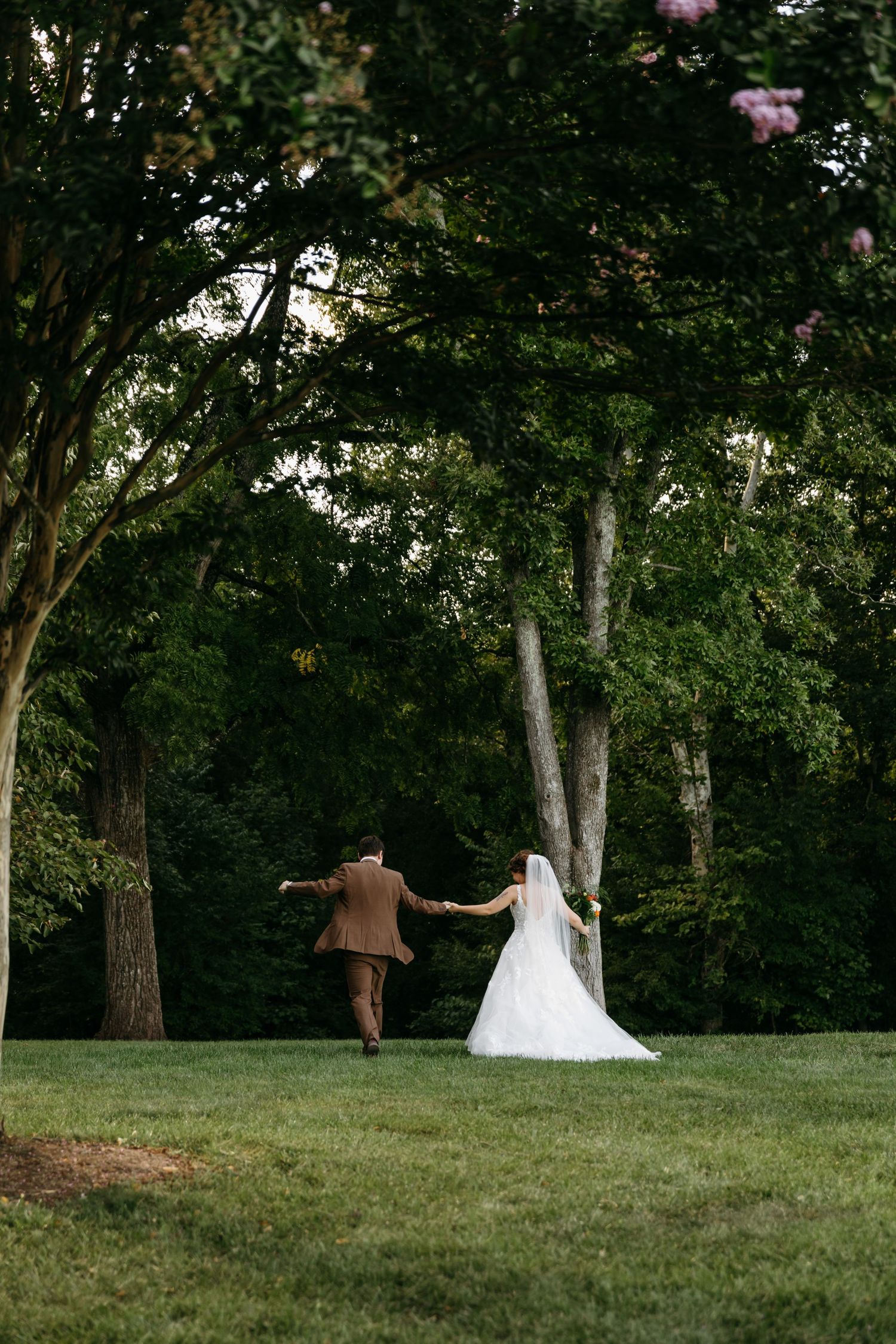 Bride and groom walk hand-in-hand through the lush green grass after their ceremony at Lovingston Winery in Virginia.