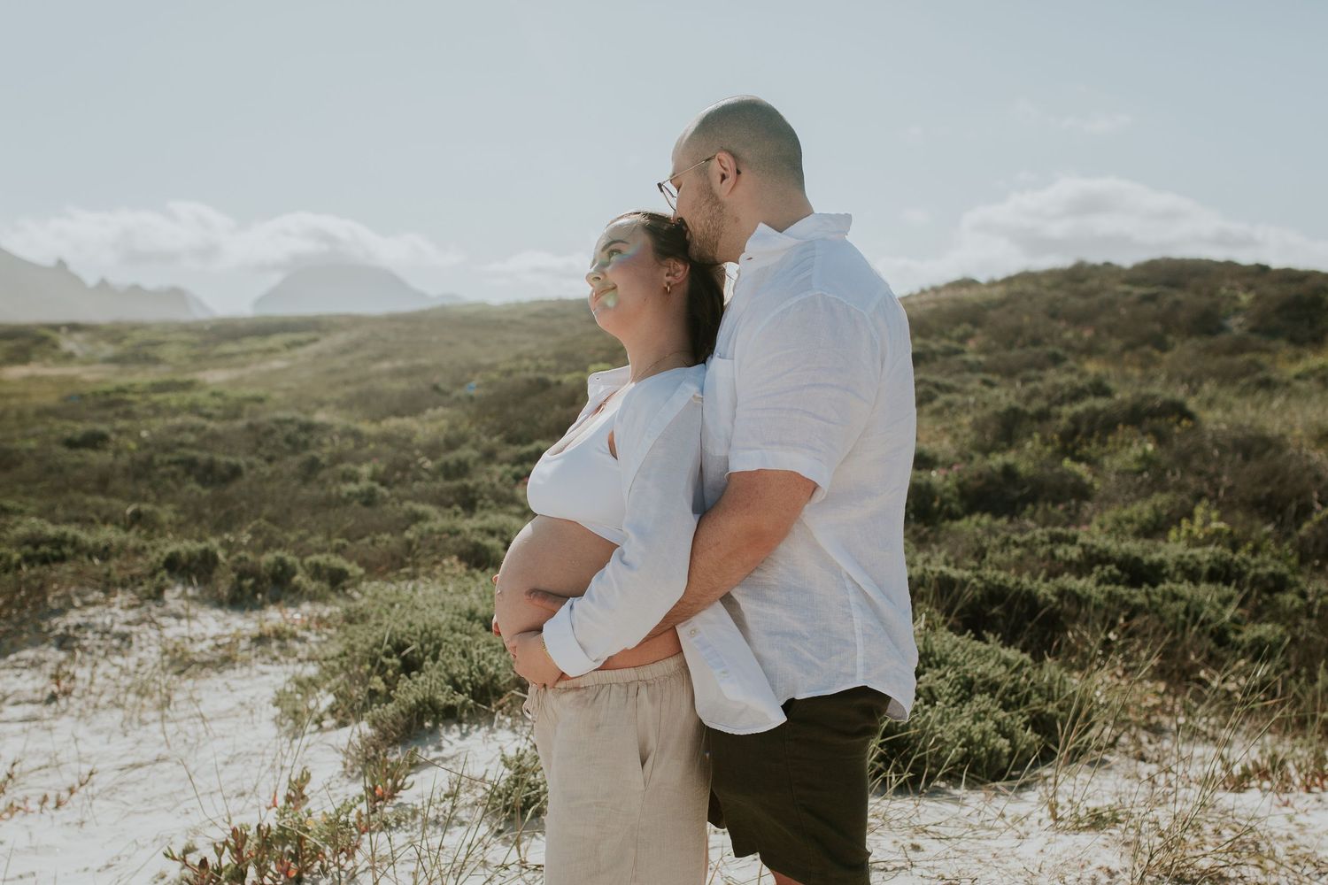 Couple embrace at the beach in maternity shoot
