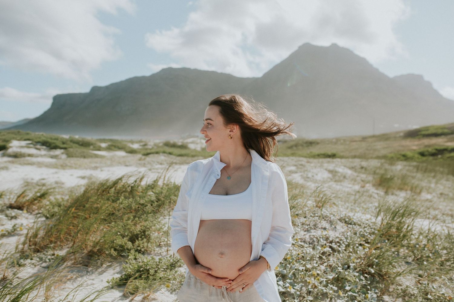 Woman smiles and relaxes as the wind blows at Muizenberg beach