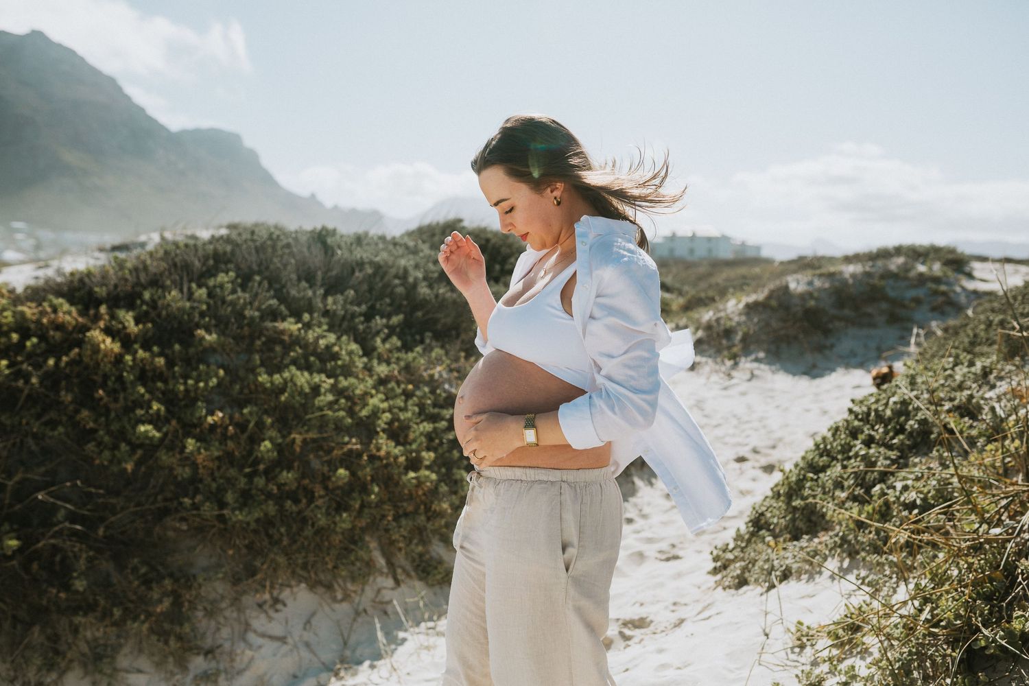 The wind sweeps the woman's hair back in her beach maternity shoot