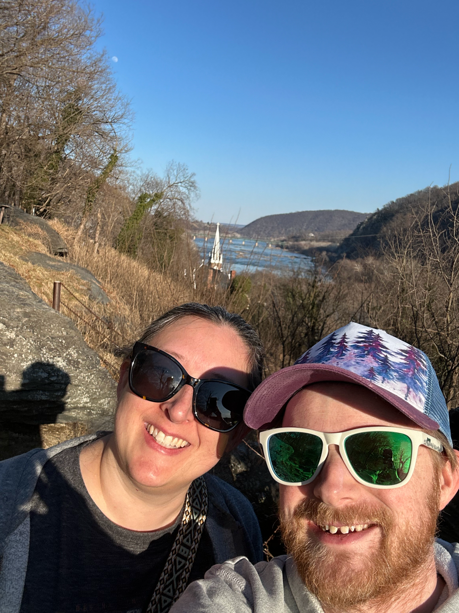 A series of selfies taken outdoors on a sunny day with mountains and trees visible in the background.