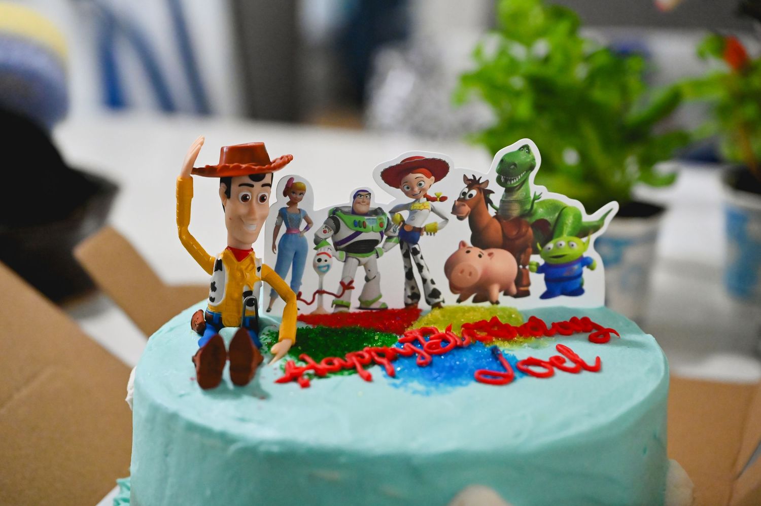 Toy Story character cake toppers including Woody, Buzz, Jessie, and Rex on a blue birthday cake.