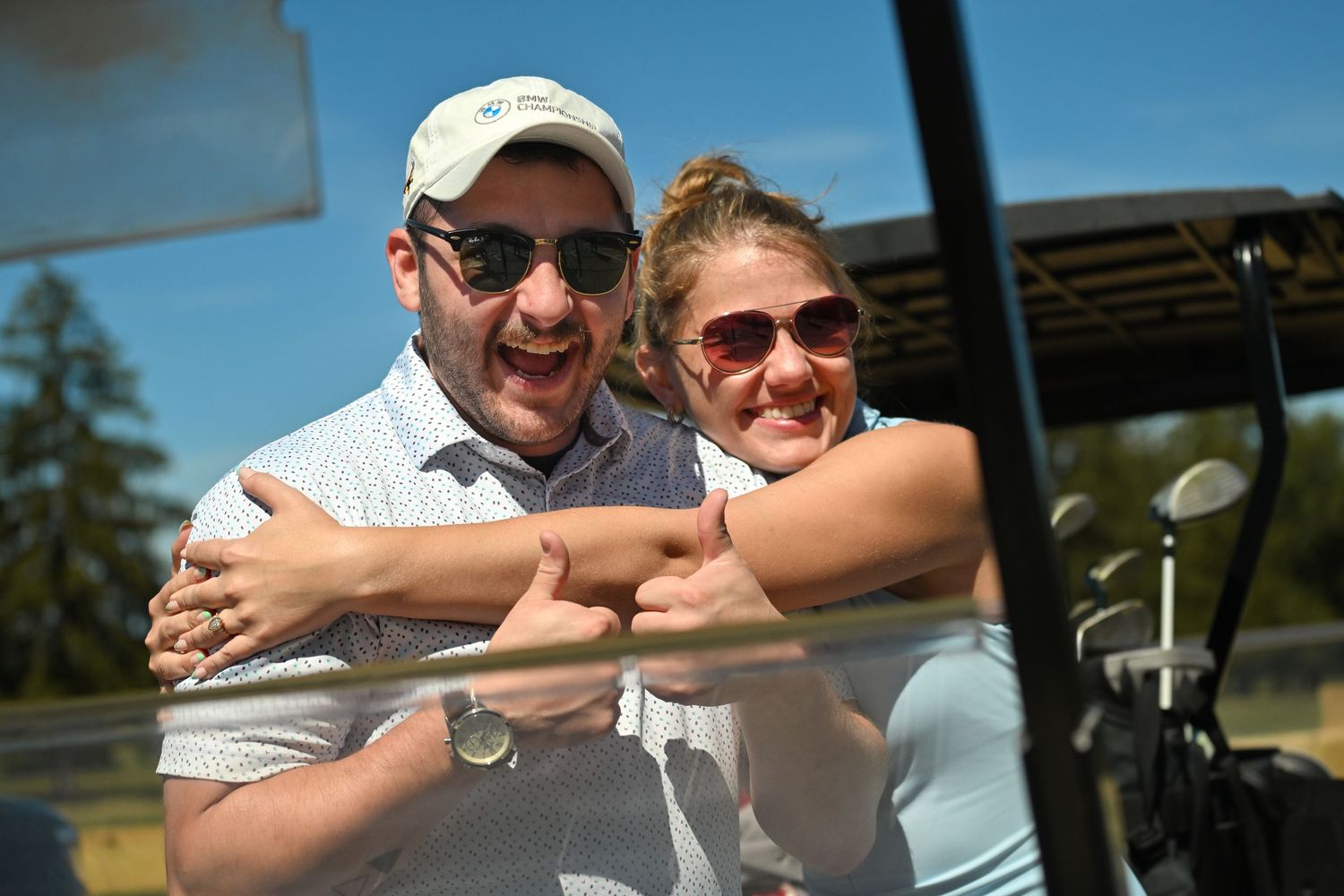 A golfing couple shares a happy moment while riding together in a golf cart on a sunny day.