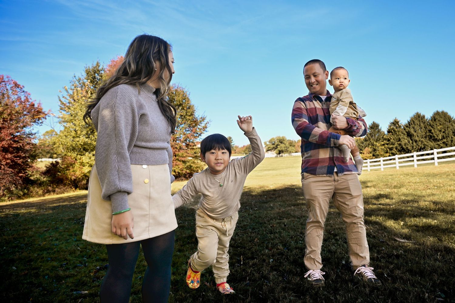 A series of outdoor family photos taken in a grassy field during golden hour with autumn colors in the background.