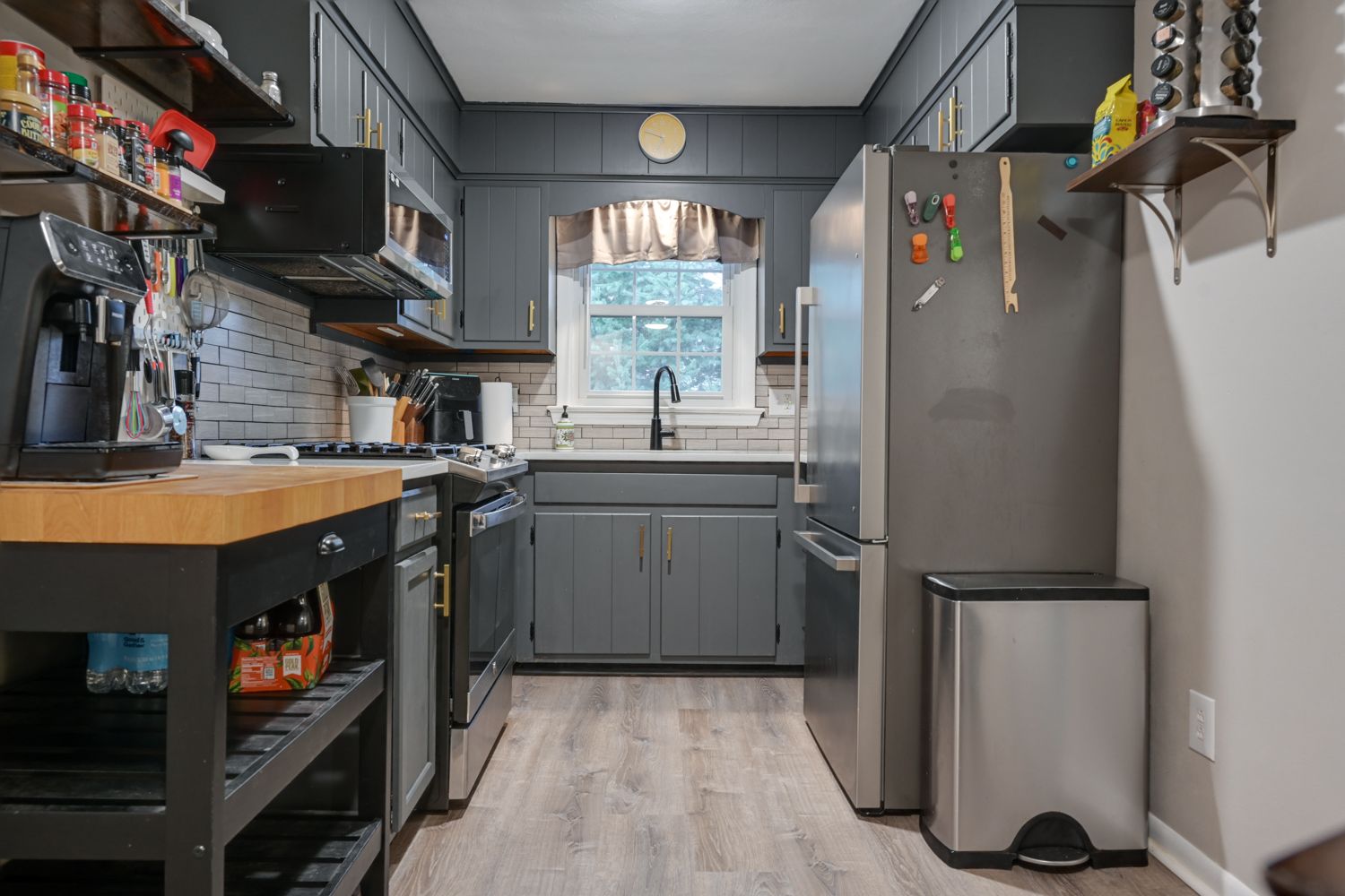 Commercial kitchen interior with stainless steel equipment and gray walls along a narrow corridor.