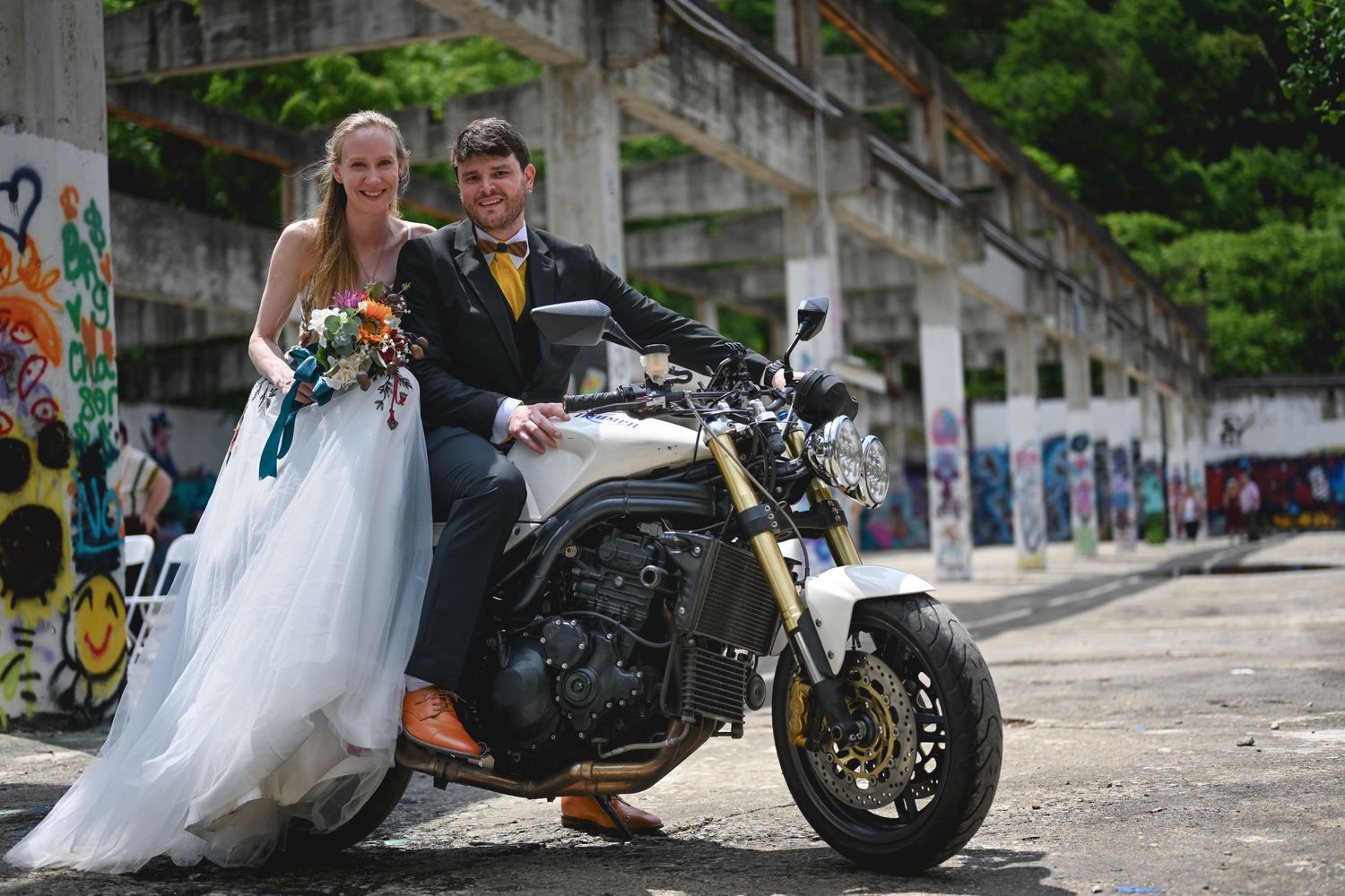 A bride in a white wedding dress sitting on a motorcycle with wedding decorations.