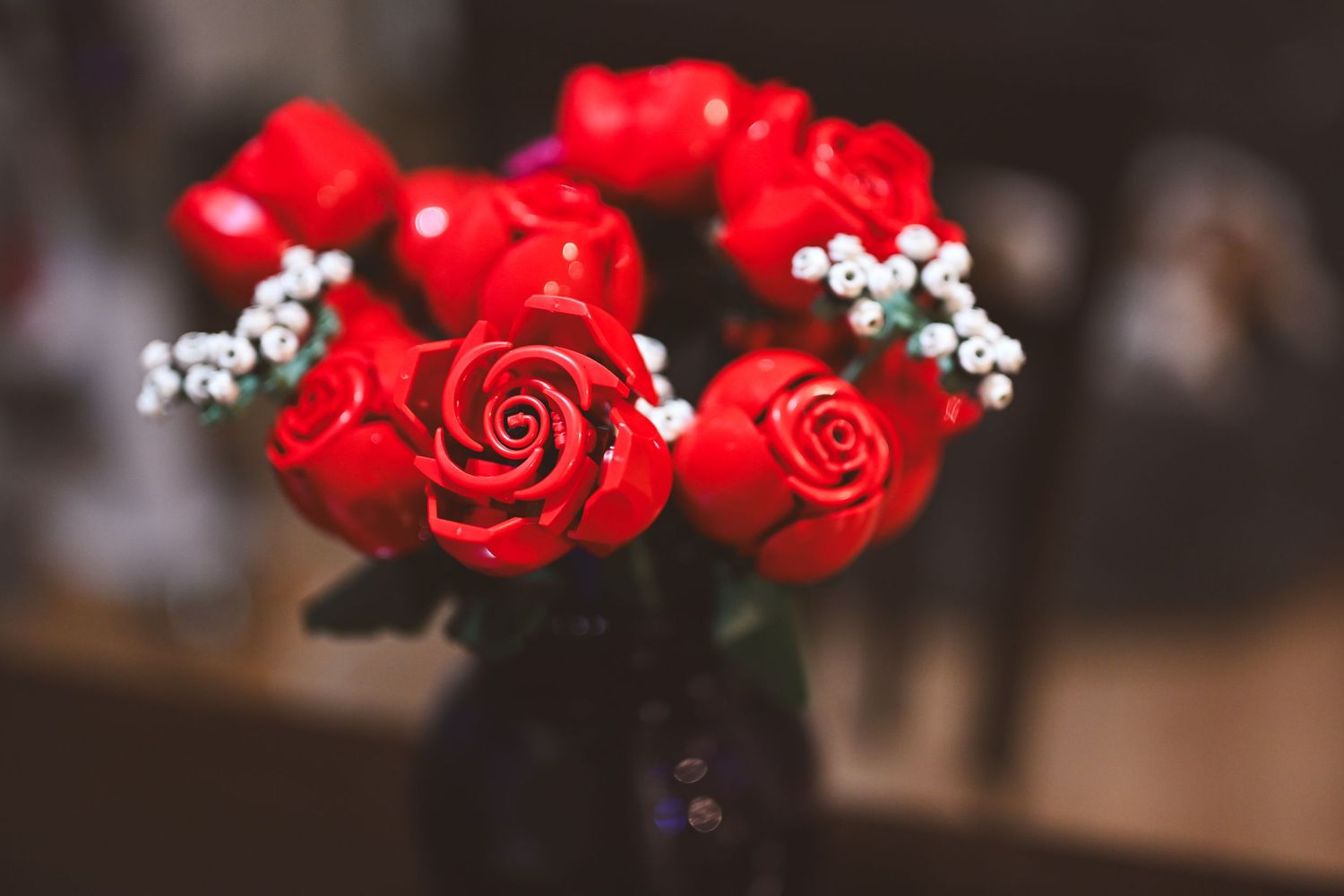 Red roses and baby's breath flowers create an elegant floral arrangement against a dark background.