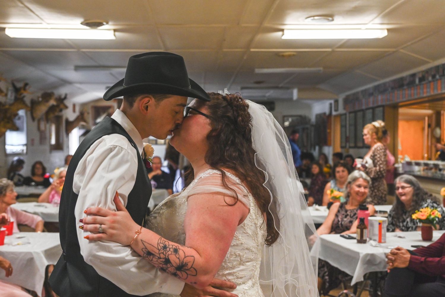 A couple at a wedding reception with guests looking on.