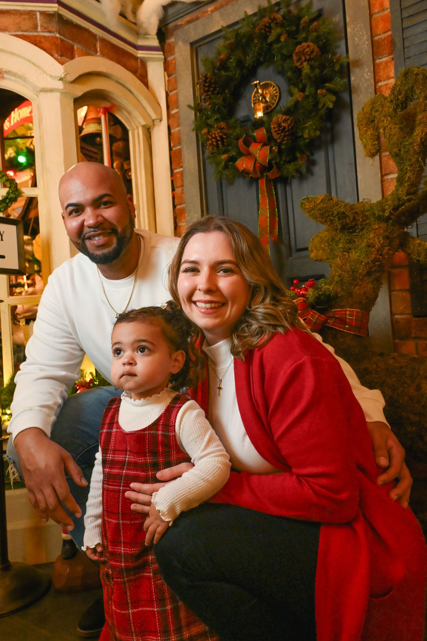 A family sits together on a porch decorated with autumn garlands and greenery during a holiday photoshoot.