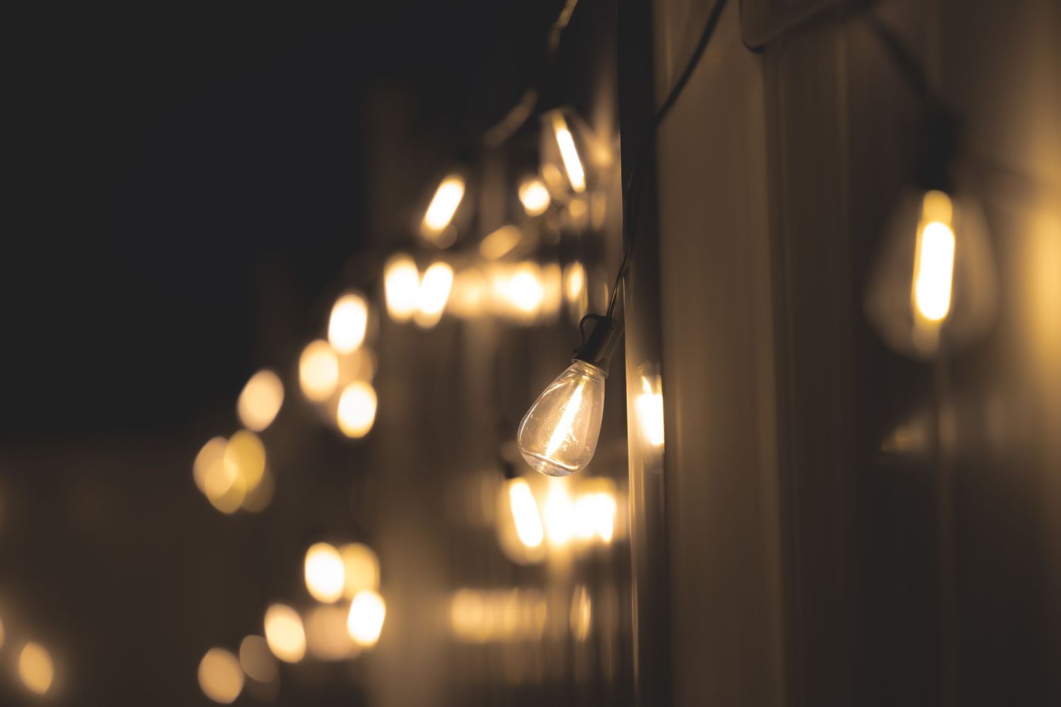 String of vintage Edison bulb lights glowing warmly against a dark background in a bokeh night setting.