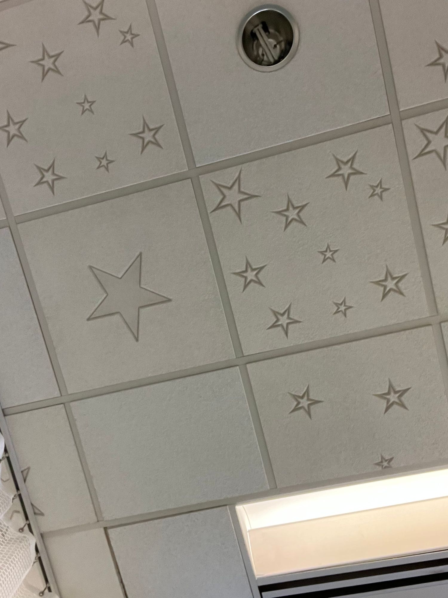 Decorative star patterns adorn the ceiling tiles in a the prep & recovery space in a clinical building.