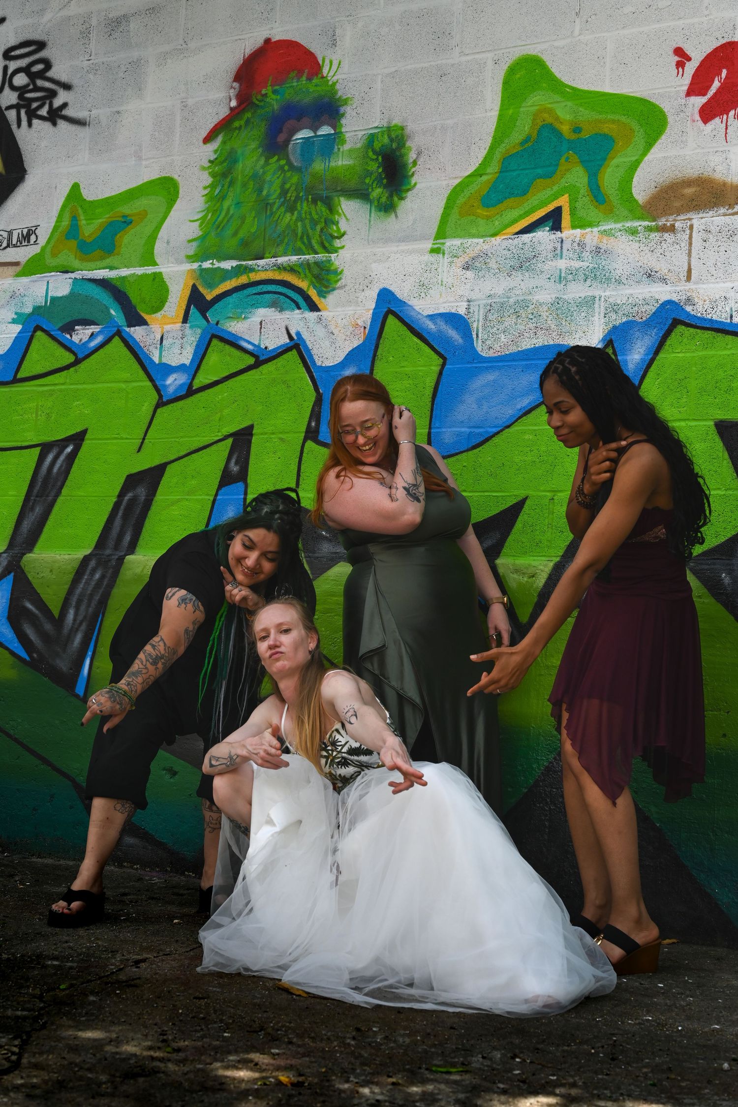 Group poses humorously in sequence along colorful graffiti wall showcasing staged motion in formal attire.