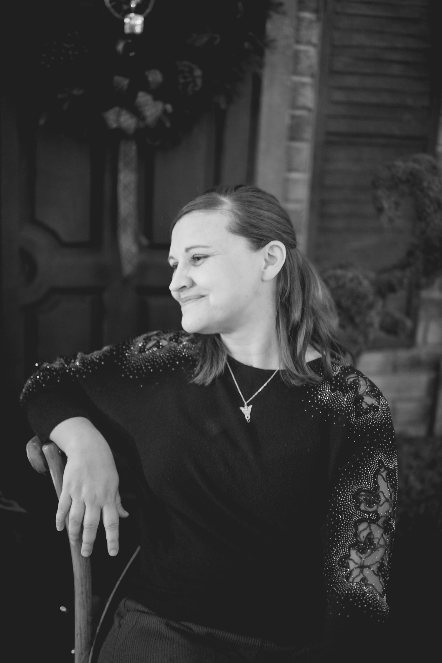 A black and white portrait of someone in dark clothing looking to the side with a contemplative expression.