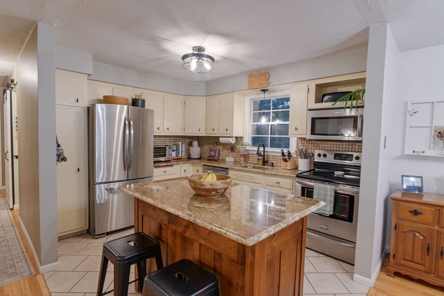 Modern kitchen and dining area with white cabinets, stainless steel appliances, and wood accents in an open floor plan.