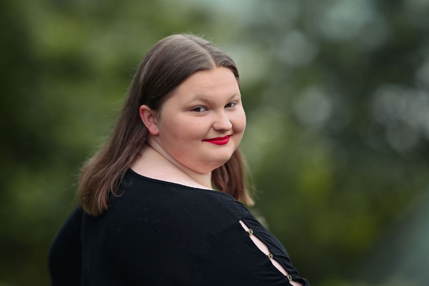 Portrait series in black business attire against blurred green background in outdoor setting.