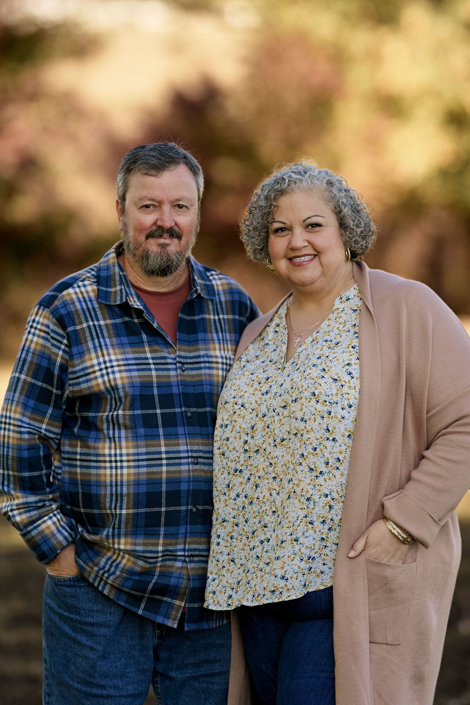 A couple in casual attire poses together outdoors with warm autumn lighting in a series of similar portraits.