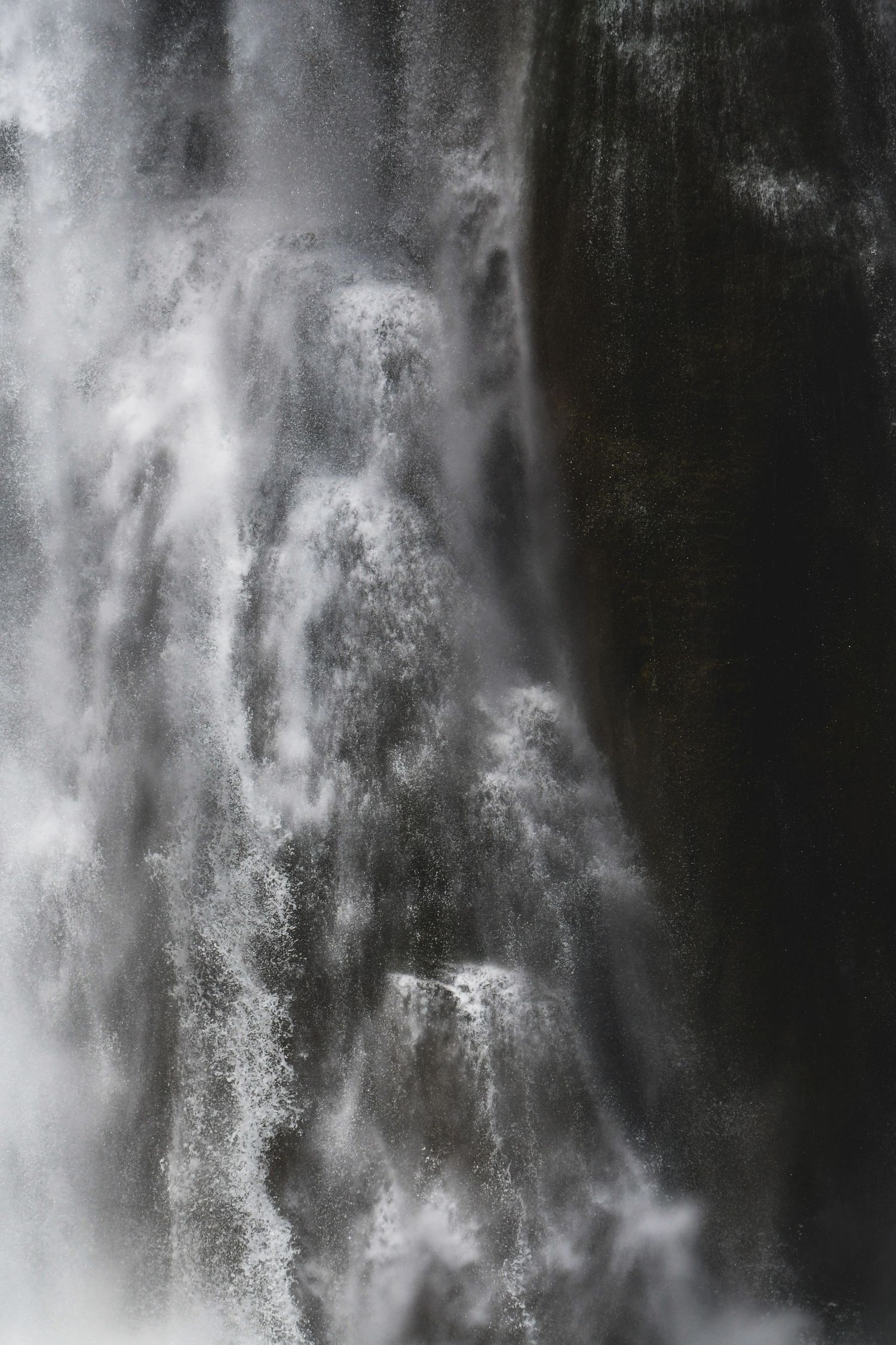 Close-up of a powerful waterfall cascading over dark rocks, with misty white water creating dramatic contrast.