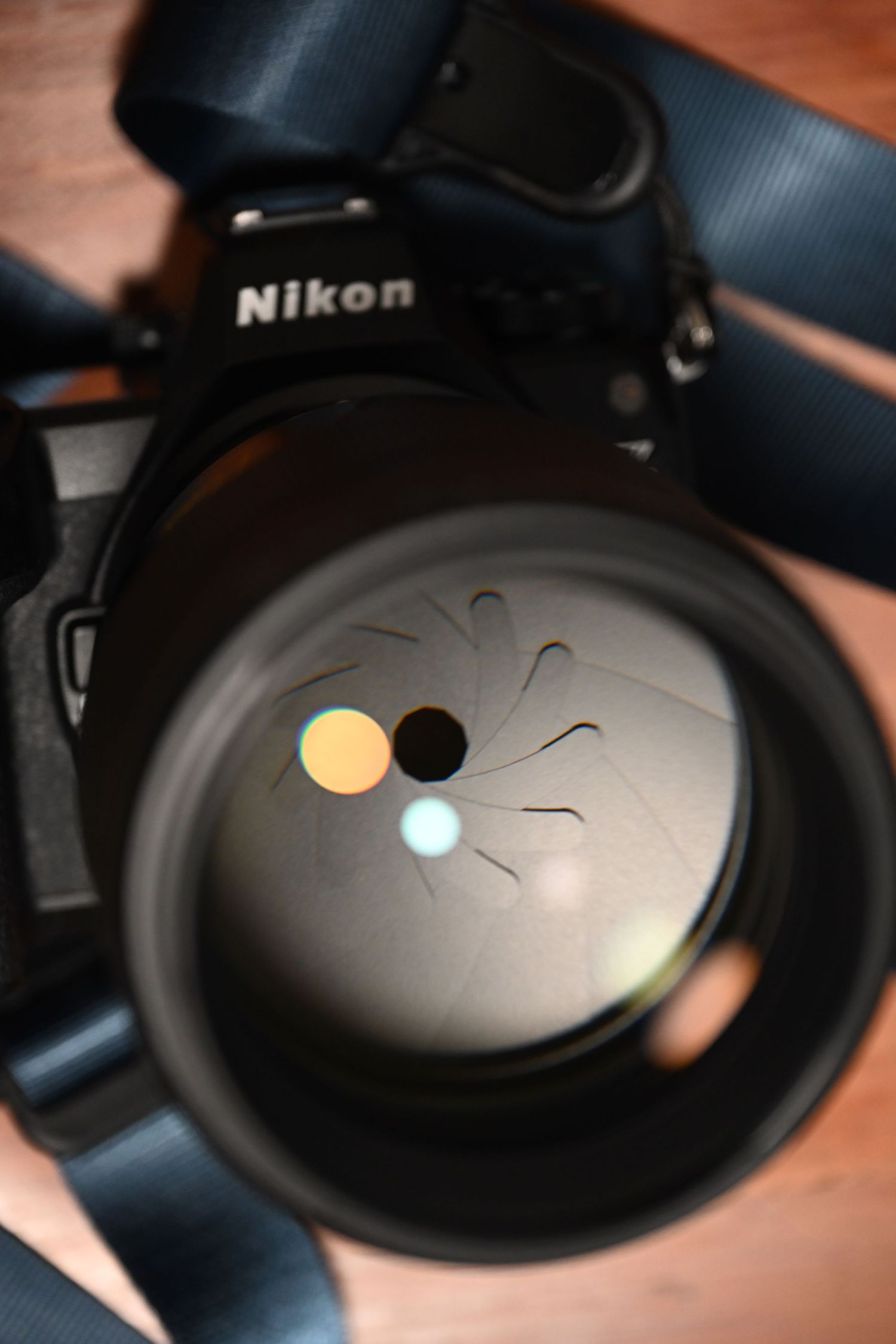 Close-up of a Nikon camera lens showing aperture blades and light reflections.