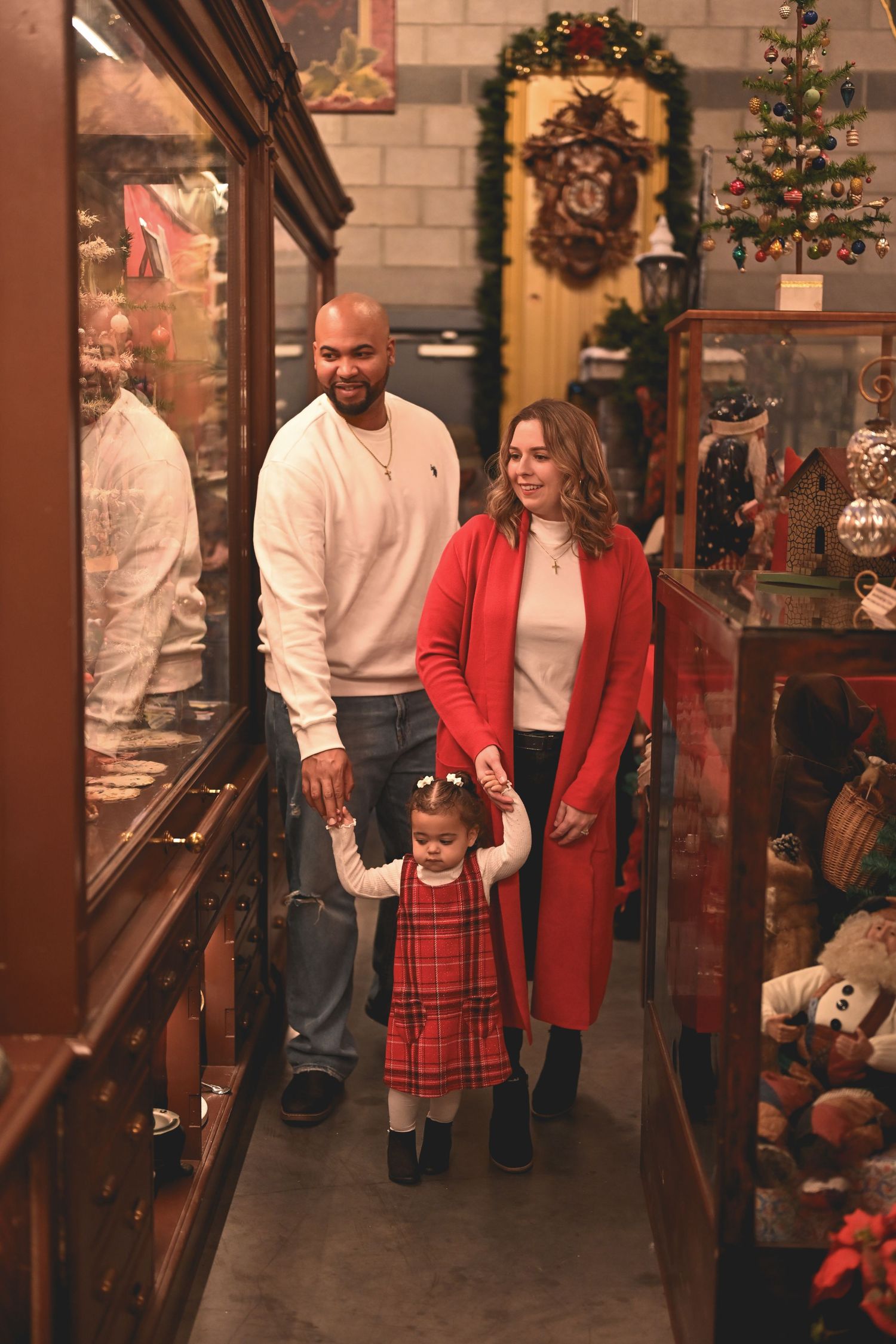 Family wearing festive red and plaid outfits poses together in a cozy holiday-decorated retail store.
