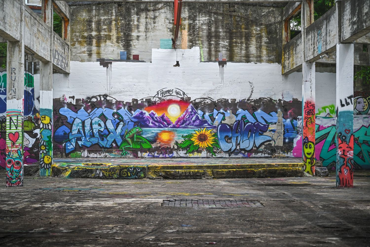 Colorful graffiti mural with vibrant blues and a red heart design adorns an abandoned concrete structure's wall.
