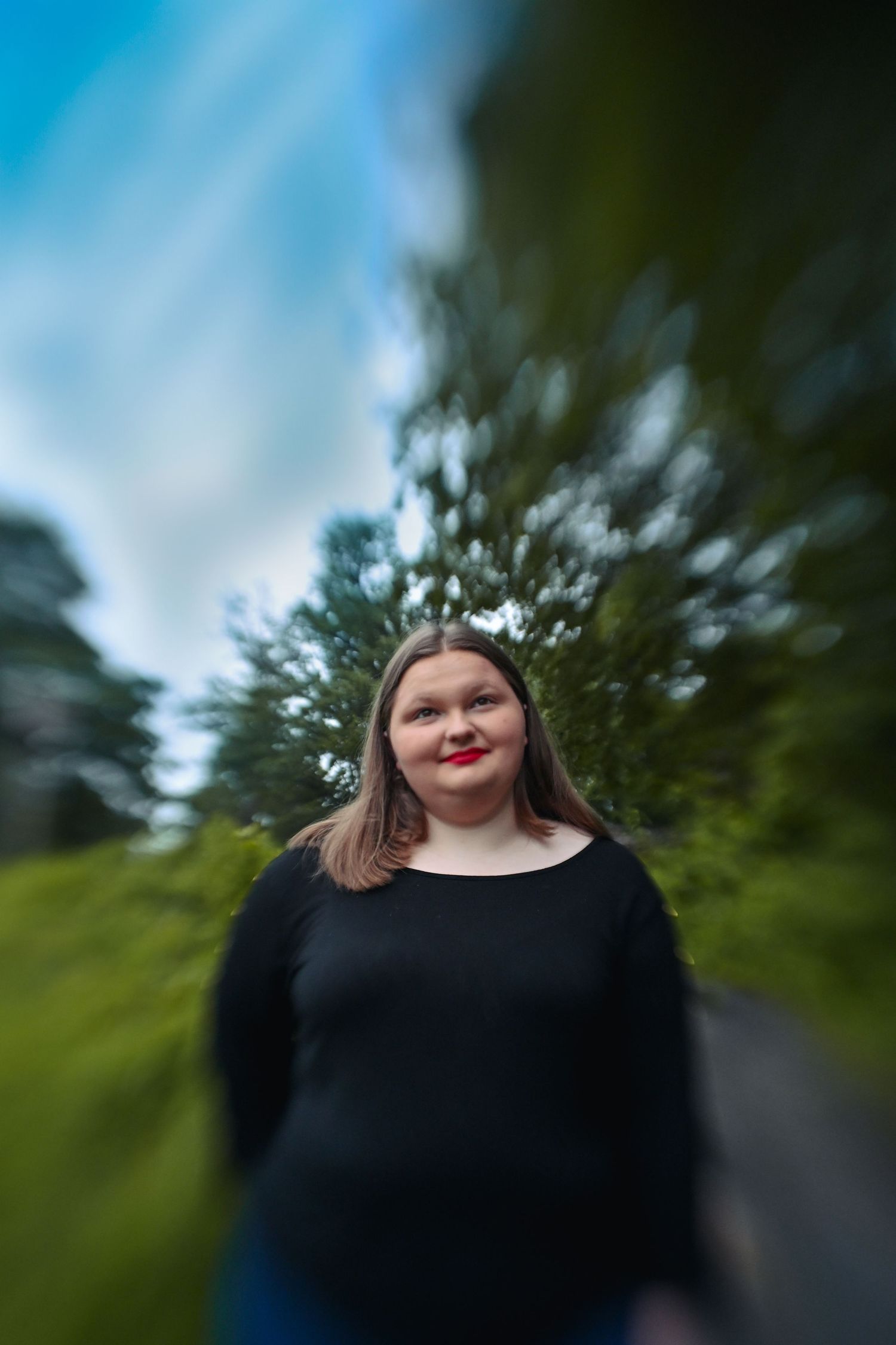 Abstract blurred forest path with blue sky creates dreamy outdoor portrait effect.
