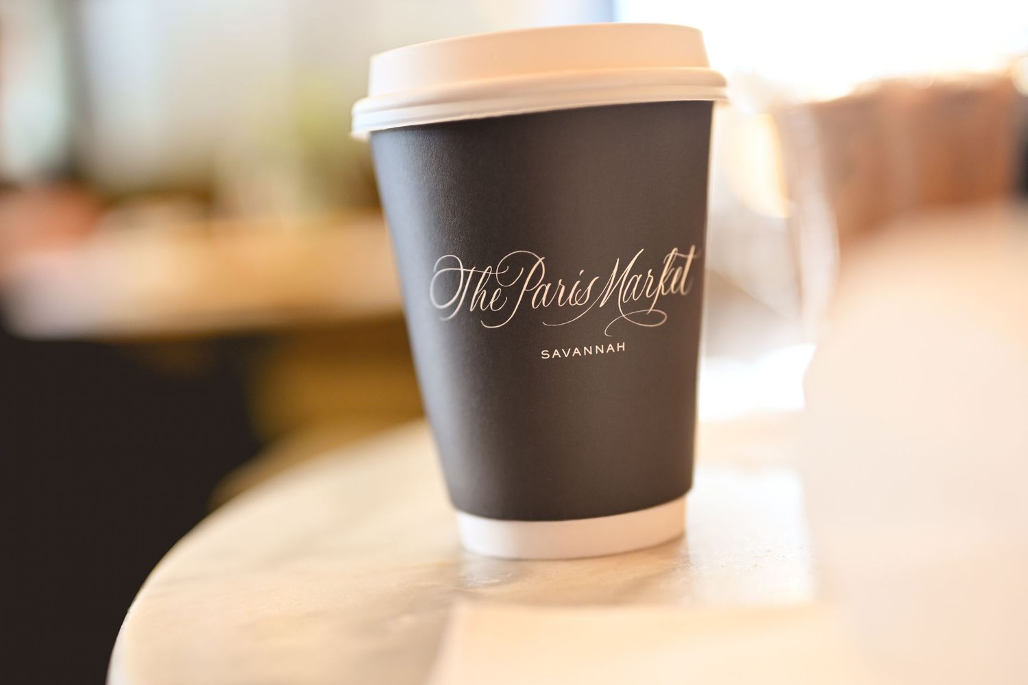 Coffee cups with brown lids sit on a counter in a row showing a repeating pattern.