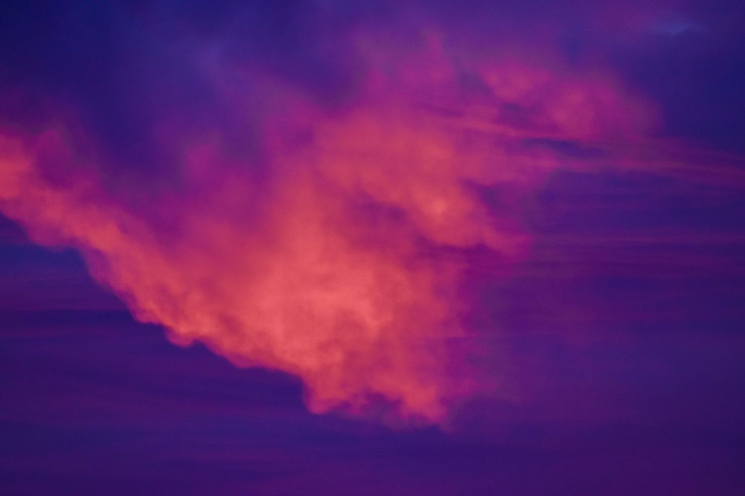 Vibrant sunset sky with dramatic pink and purple clouds glowing in fiery orange and magenta hues.