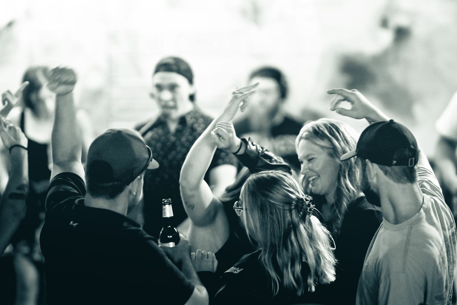 A black and white photo of people dancing and socializing at a lively party or concert gathering.