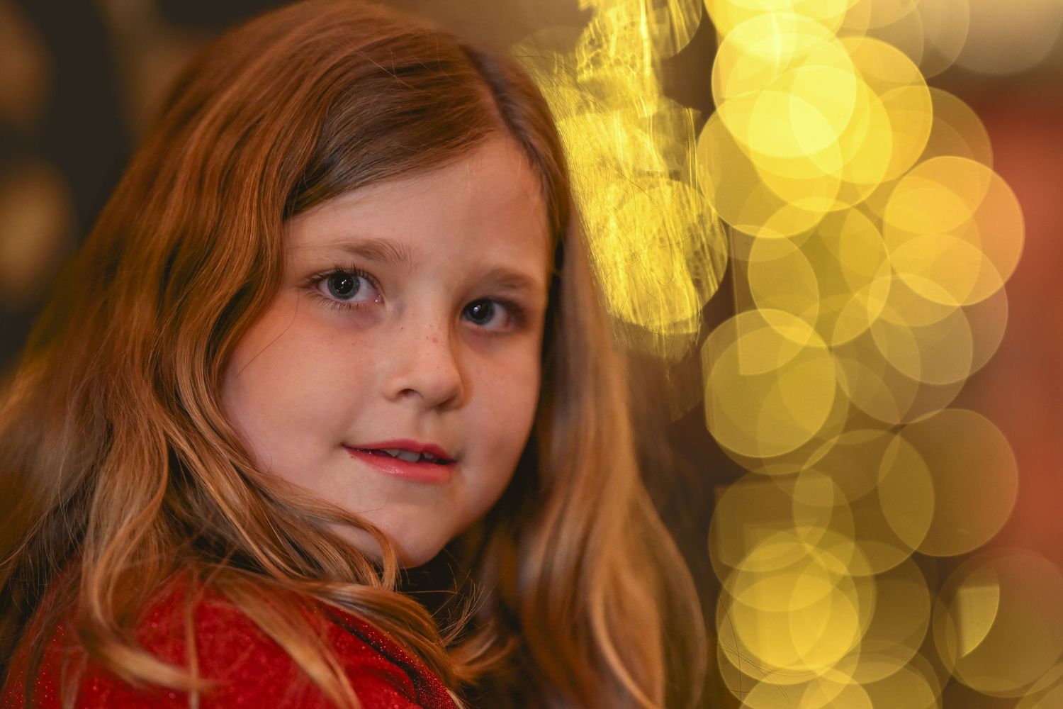 Portrait with red clothing against a blurred background of golden bokeh lights.