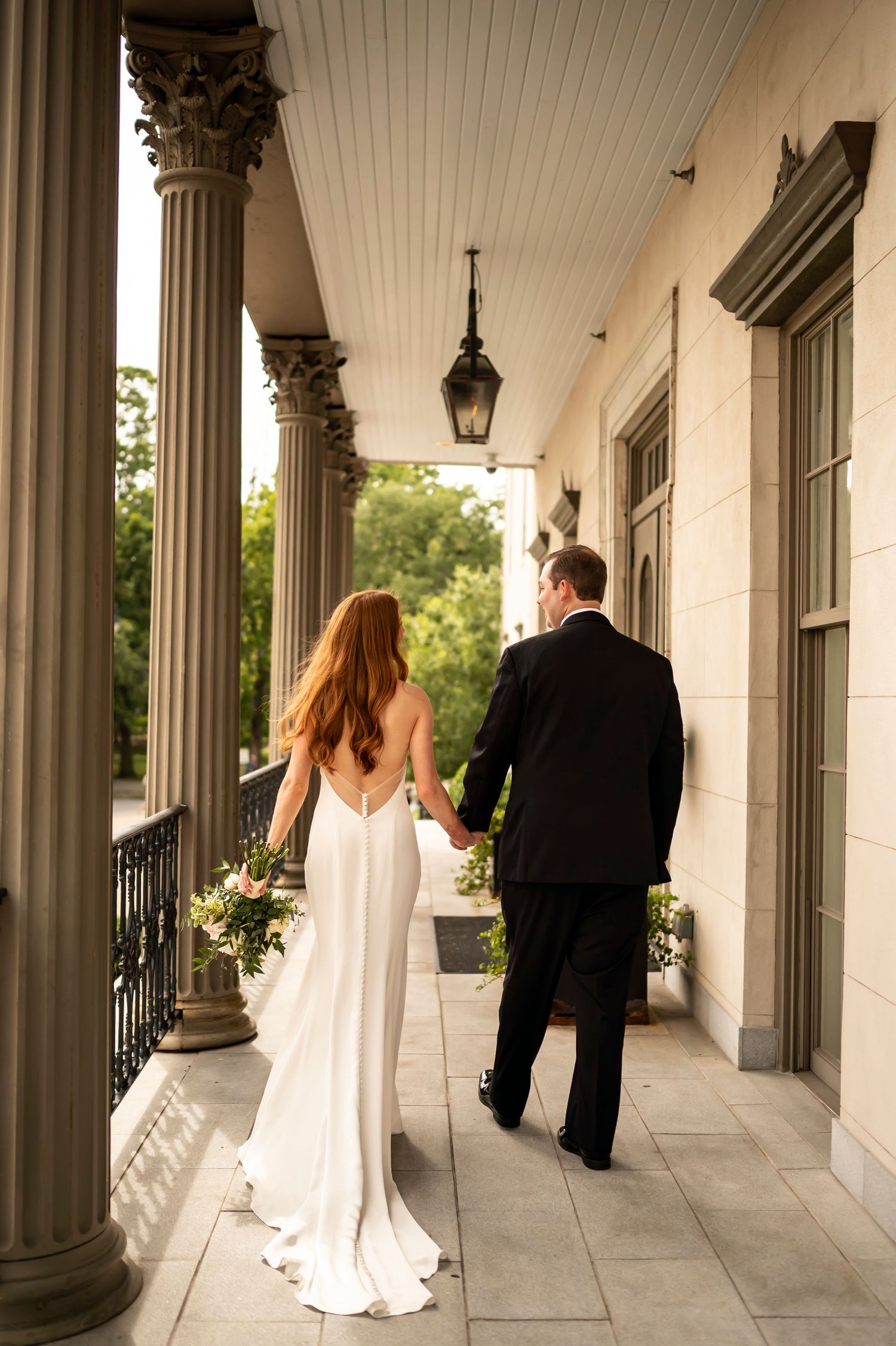 Bride and groom walking along an elegant columned portico at their wedding venue, photographed from multiple angles.