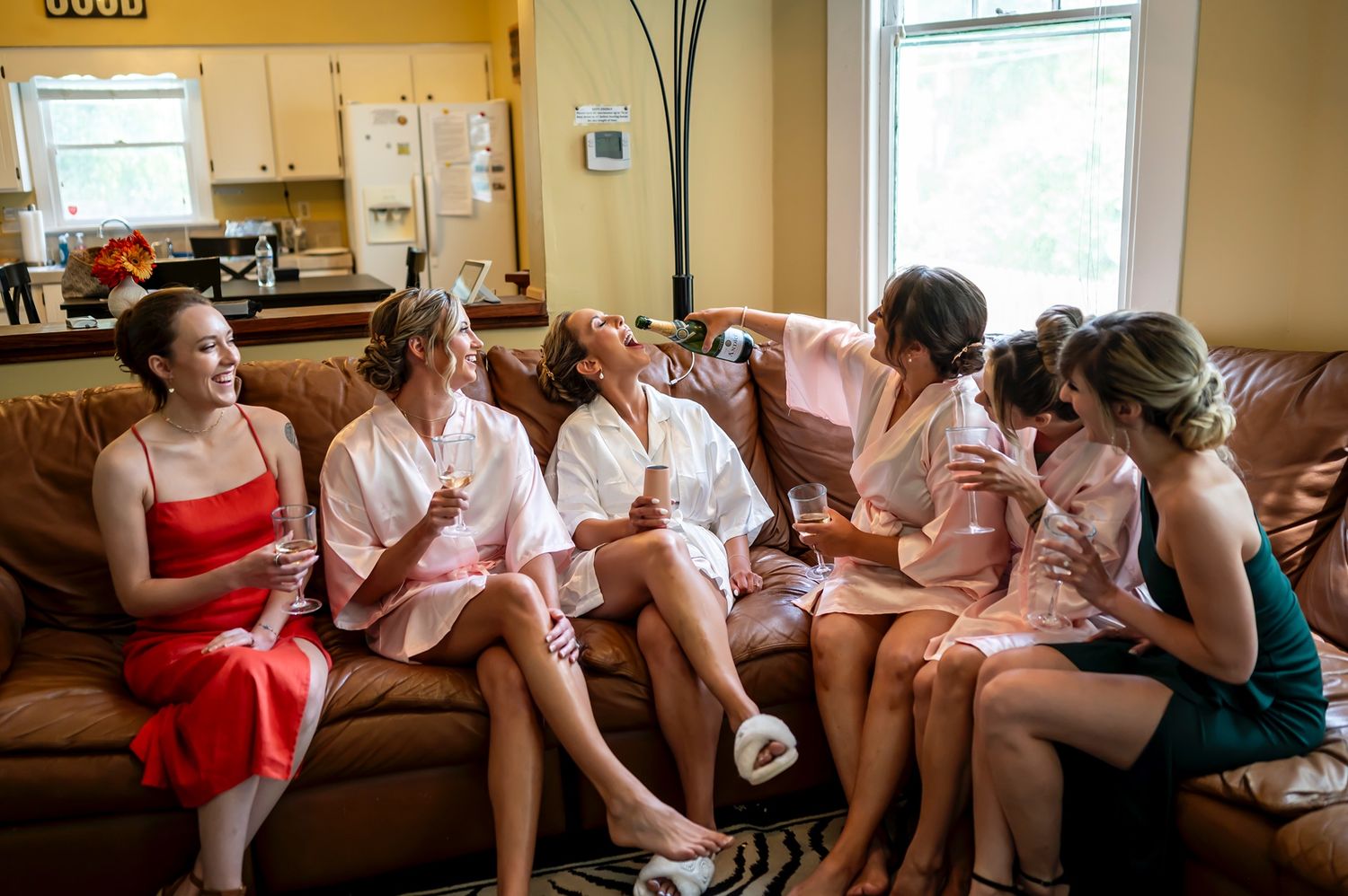 Several people seated in a row on a couch having lively interactions and appearing to be in good spirits.