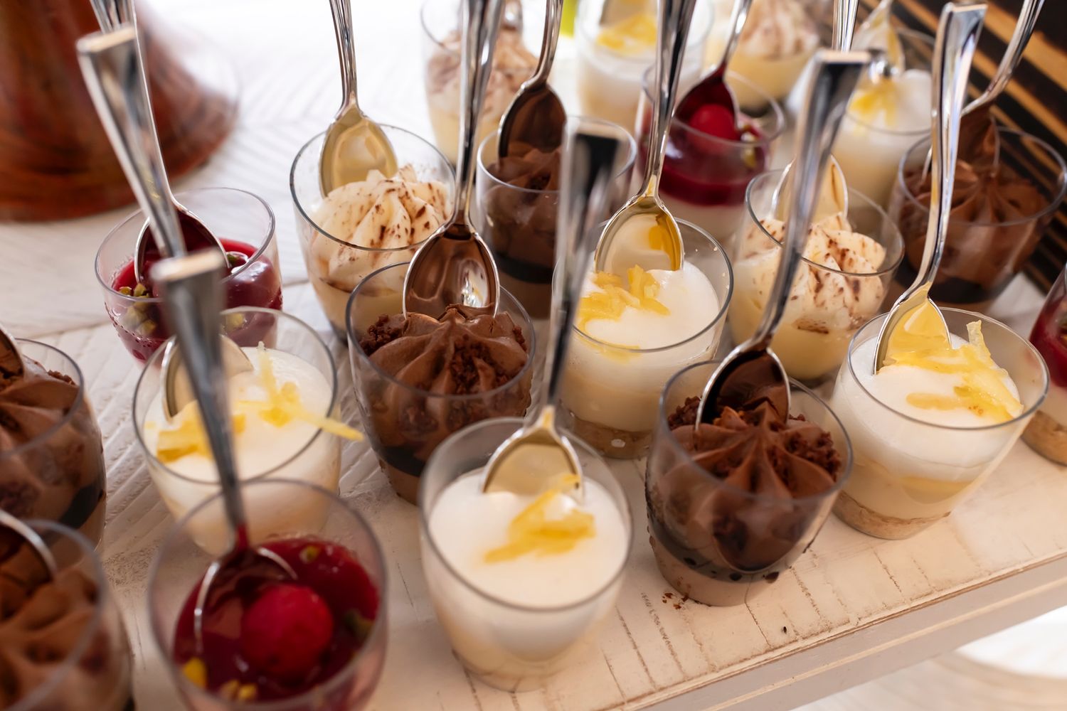 An assortment of elegant dessert shooters with mousse and fruit toppings served in small glass containers.