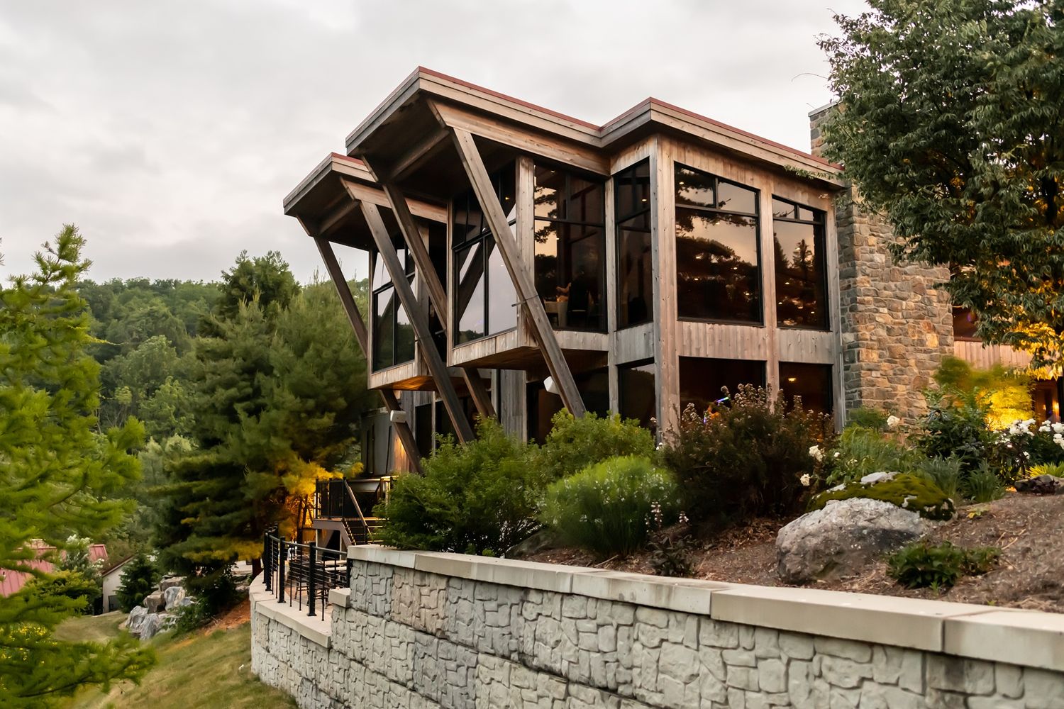 A rustic modern event venue with stone and wood architecture surrounded by mountain landscape.