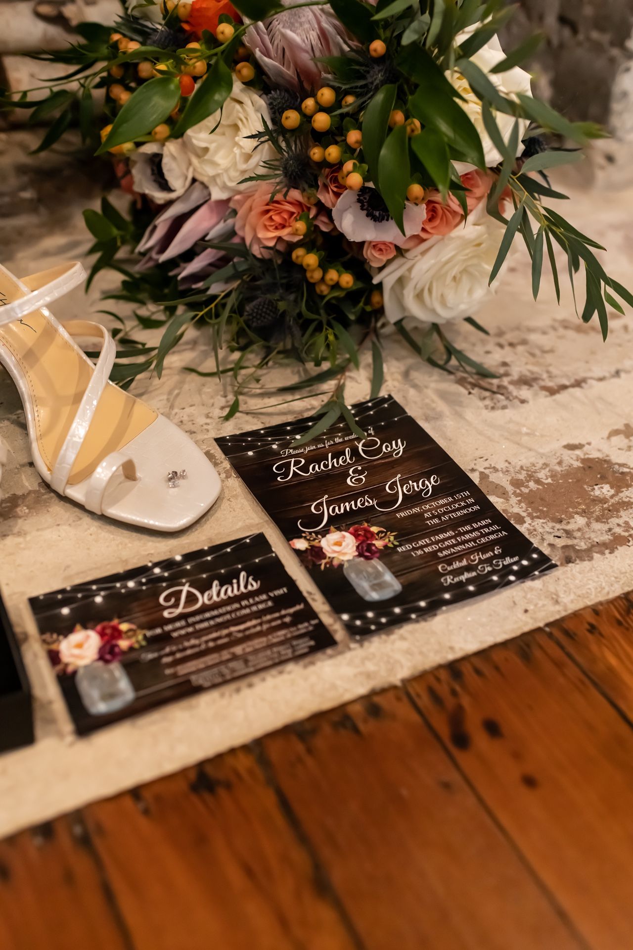 Wedding invitation cards with elegant black design laid on wooden surface with floral arrangements and berries on top.