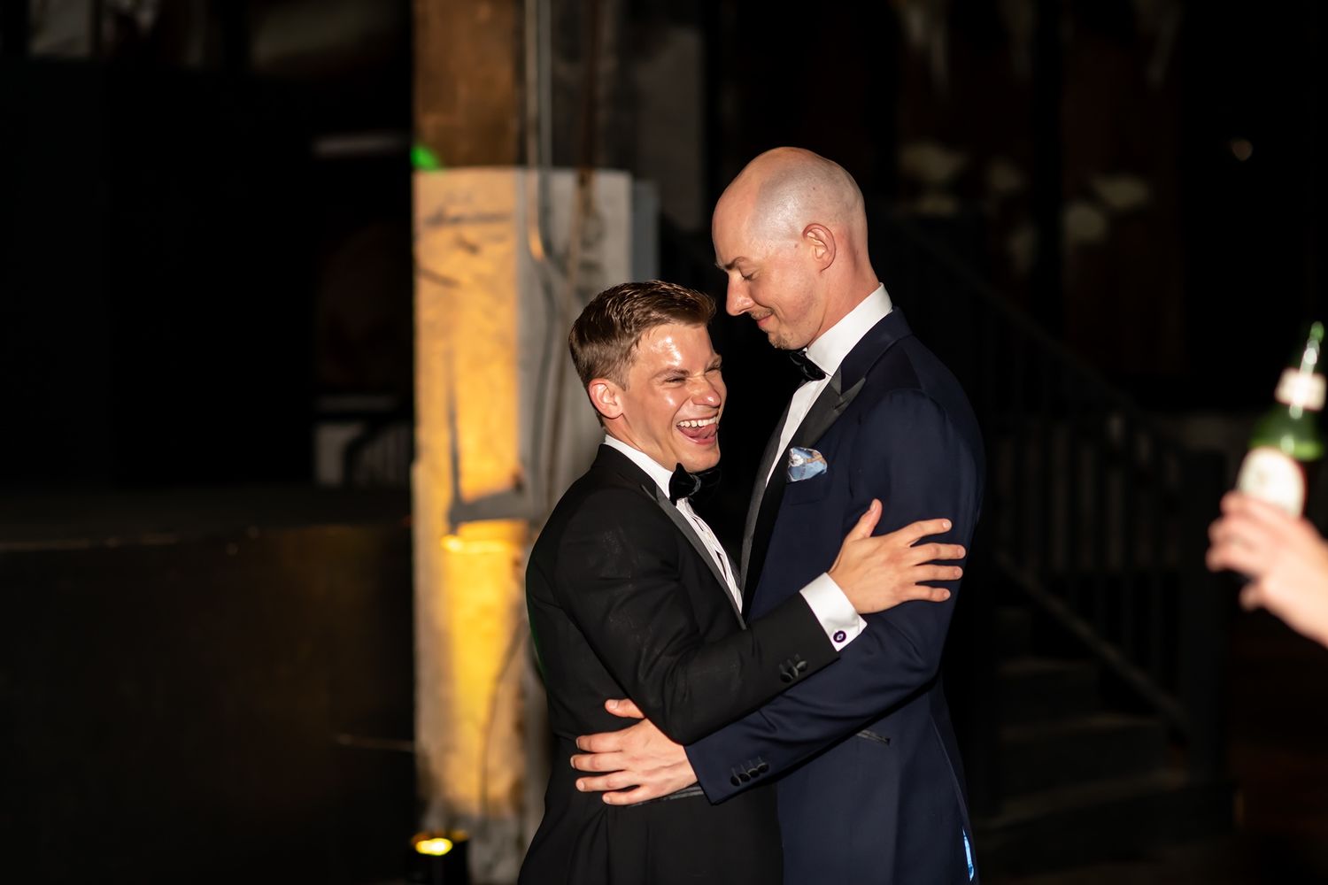 Two people in formal attire embrace and share an intimate moment during an elegant evening celebration.