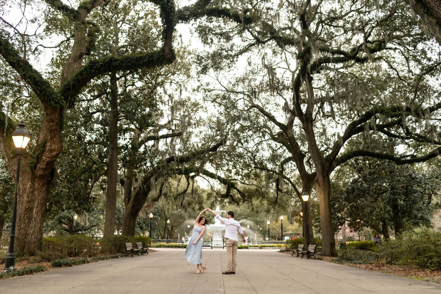 Engagement portraits with a panoramic view of a majestic oak tree canopy at Forsyth Park stretching over a winding pathway.