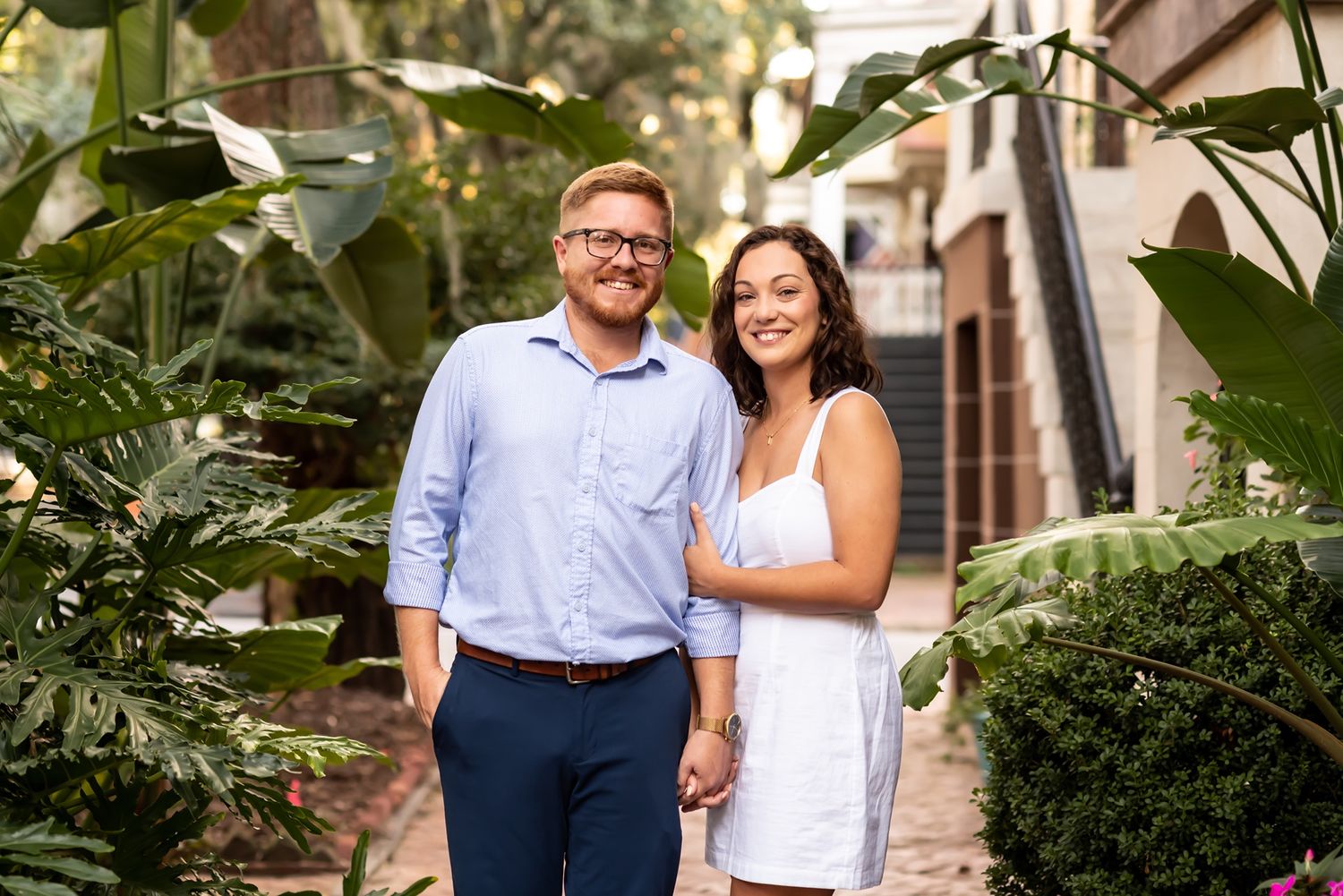 Engaged couple stands together in a lush garden setting during their outdoor portrait session.