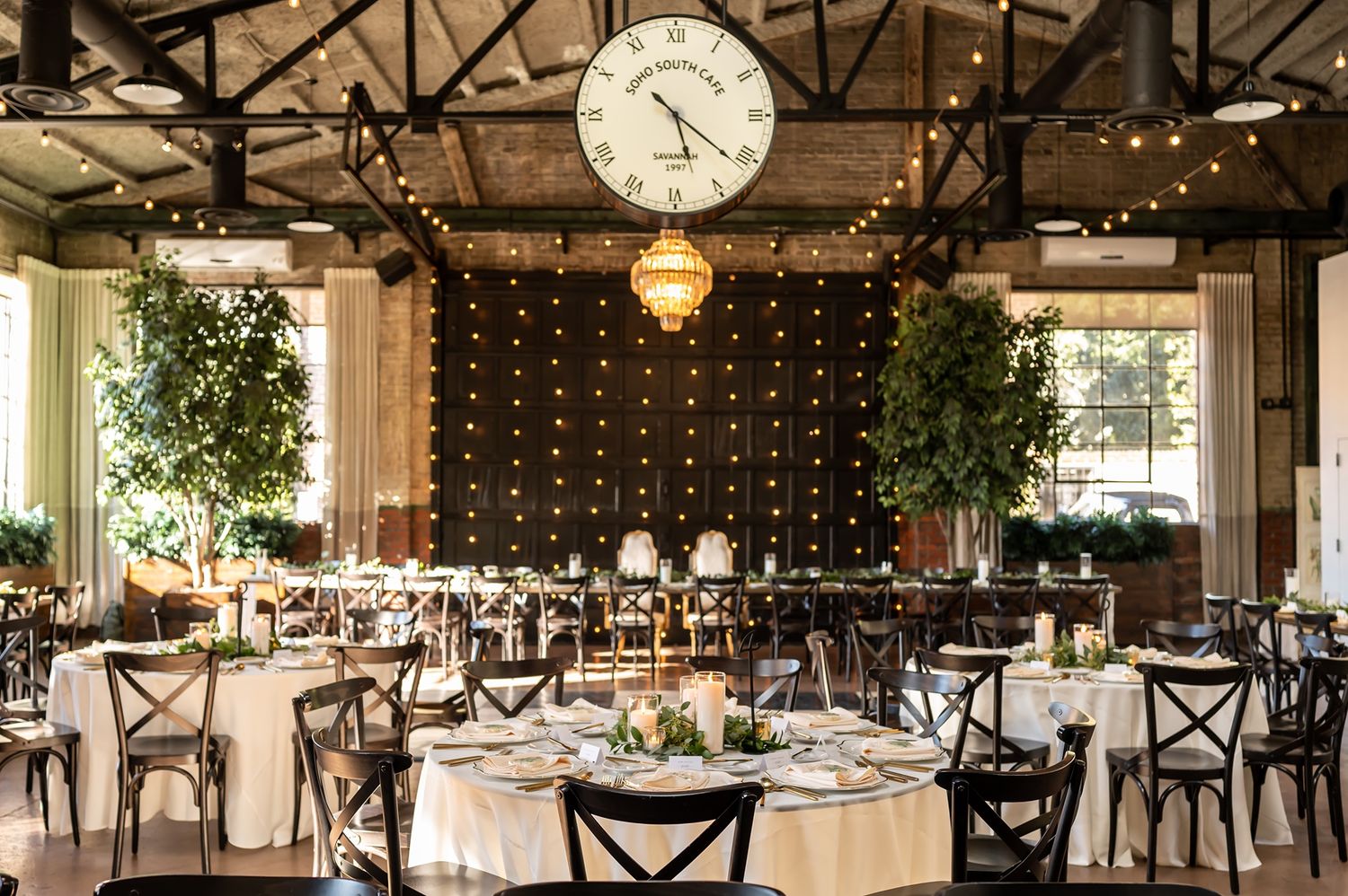 Rustic wedding reception venue with exposed wooden beams, string lights, and elegant table settings for an industrial chic celebration.