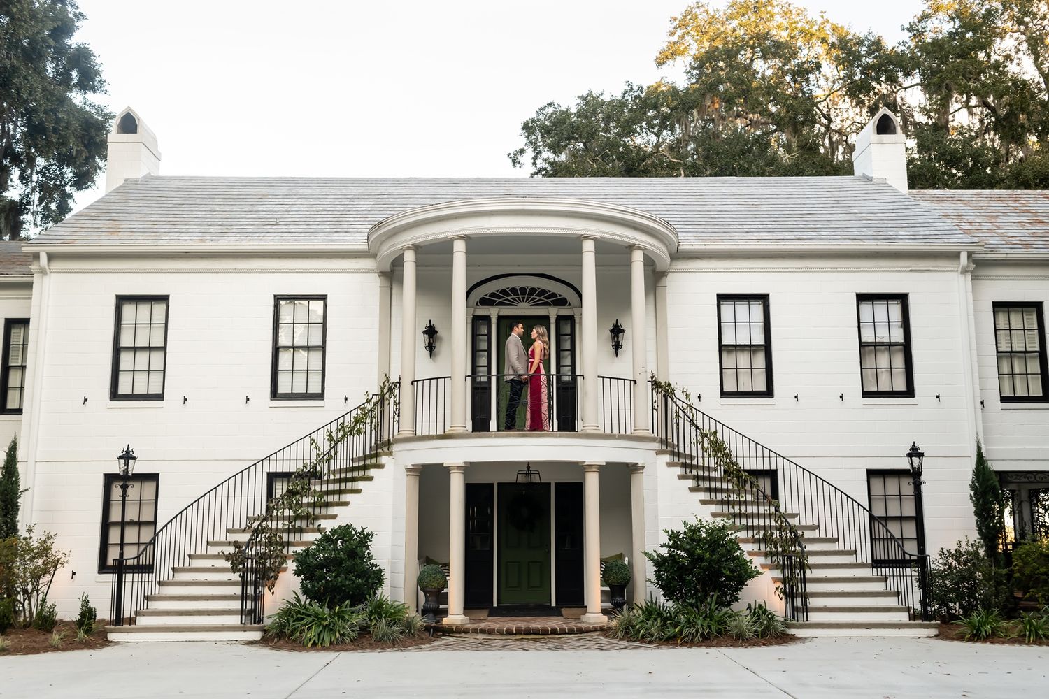 White antebellum style mansion with grand pillars and symmetrical dual staircases leading to the entrance.
