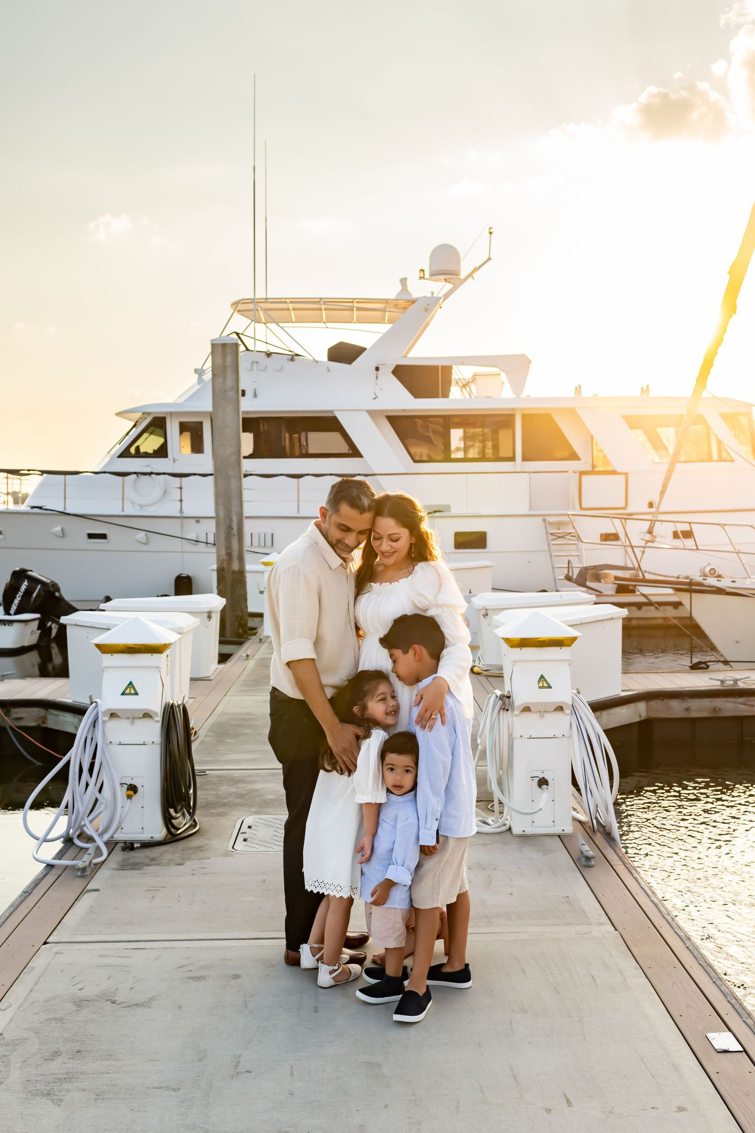 Family photoshoot at sunset on a marina dock with luxury boats in background.