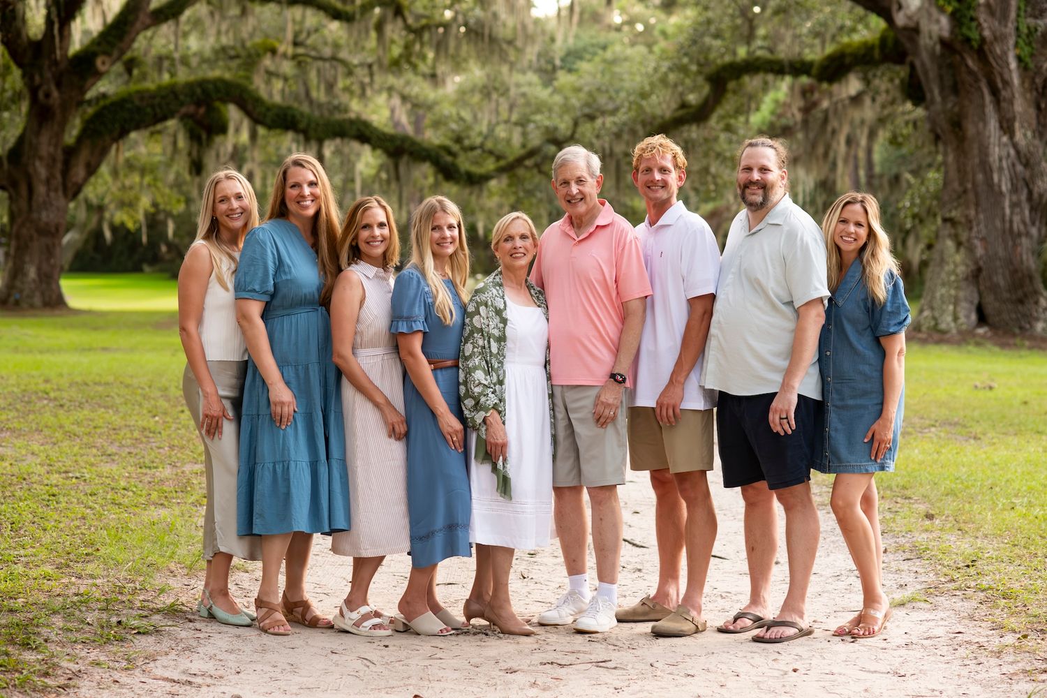 Large family group portrait outdoors under Spanish moss oak trees on a scenic Southern landscape path.
