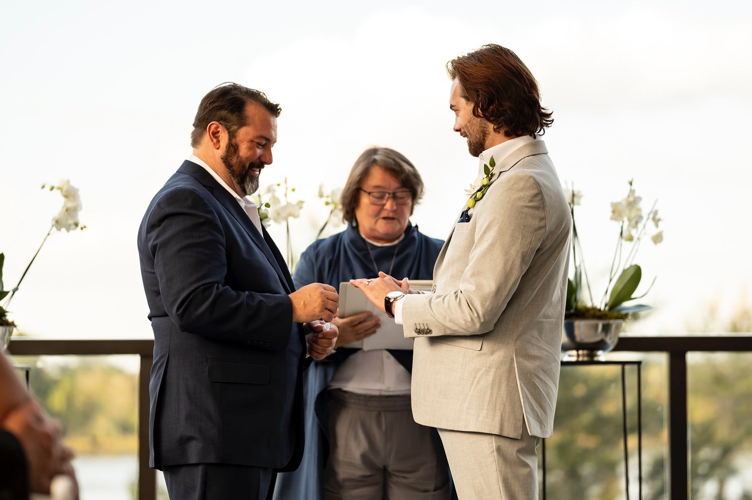 Three people sharing a moment on an outdoor terrace during what appears to be a wedding ceremony.