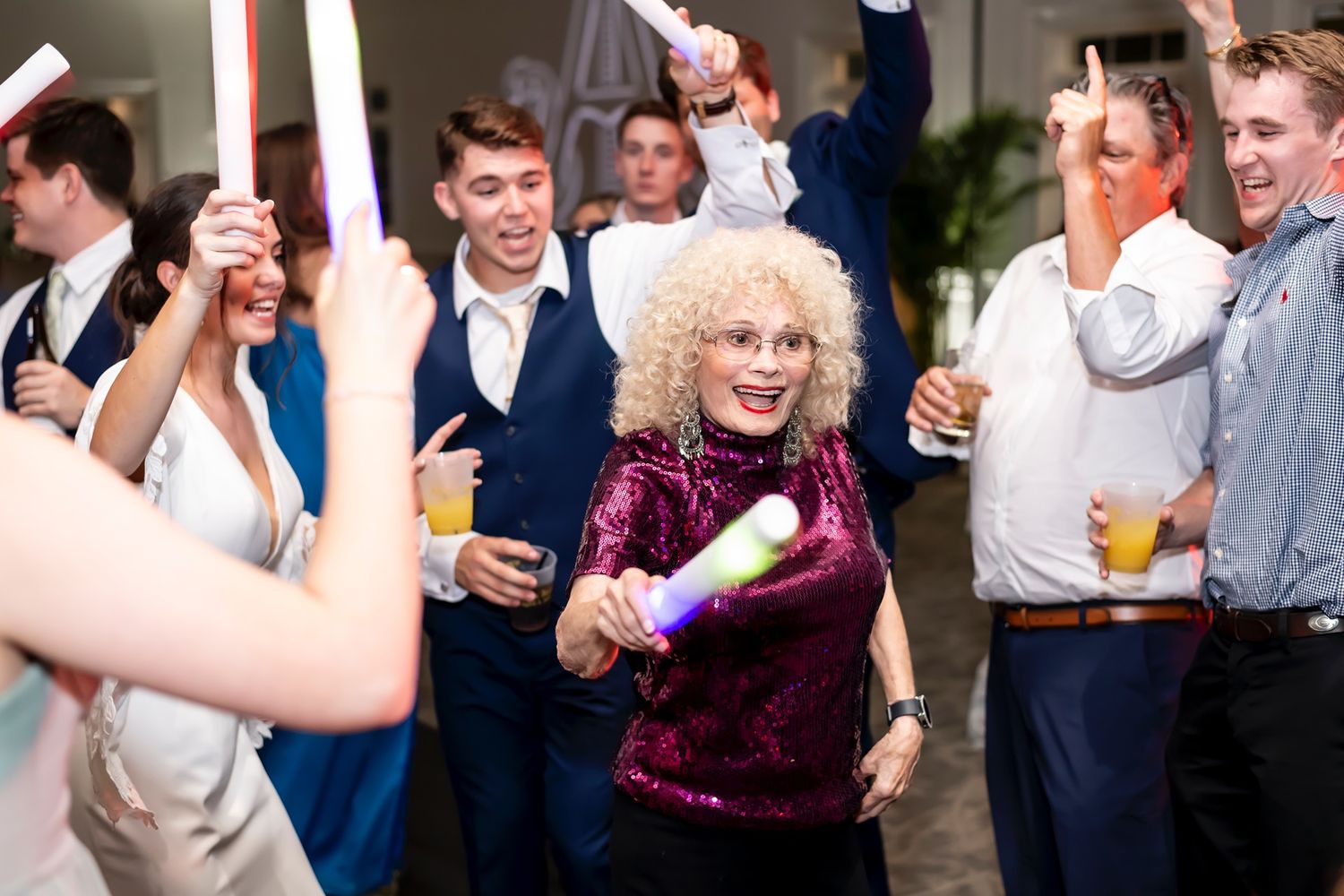 Wedding guests on the dance floor celebrate and enjoy drinks during a lively reception party.