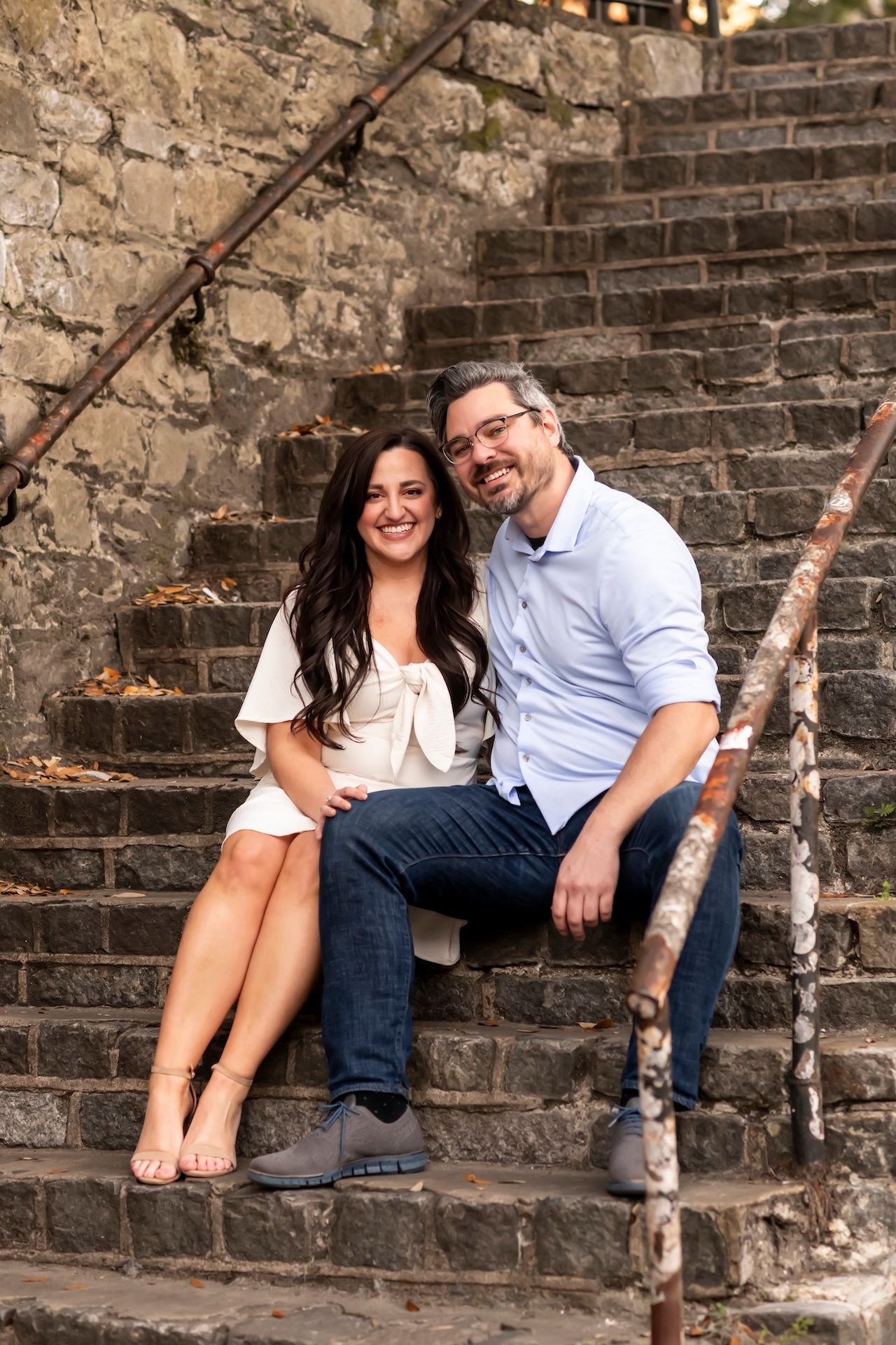 A couple shares romantic moments while sitting on old stone steps during an outdoor photo session.