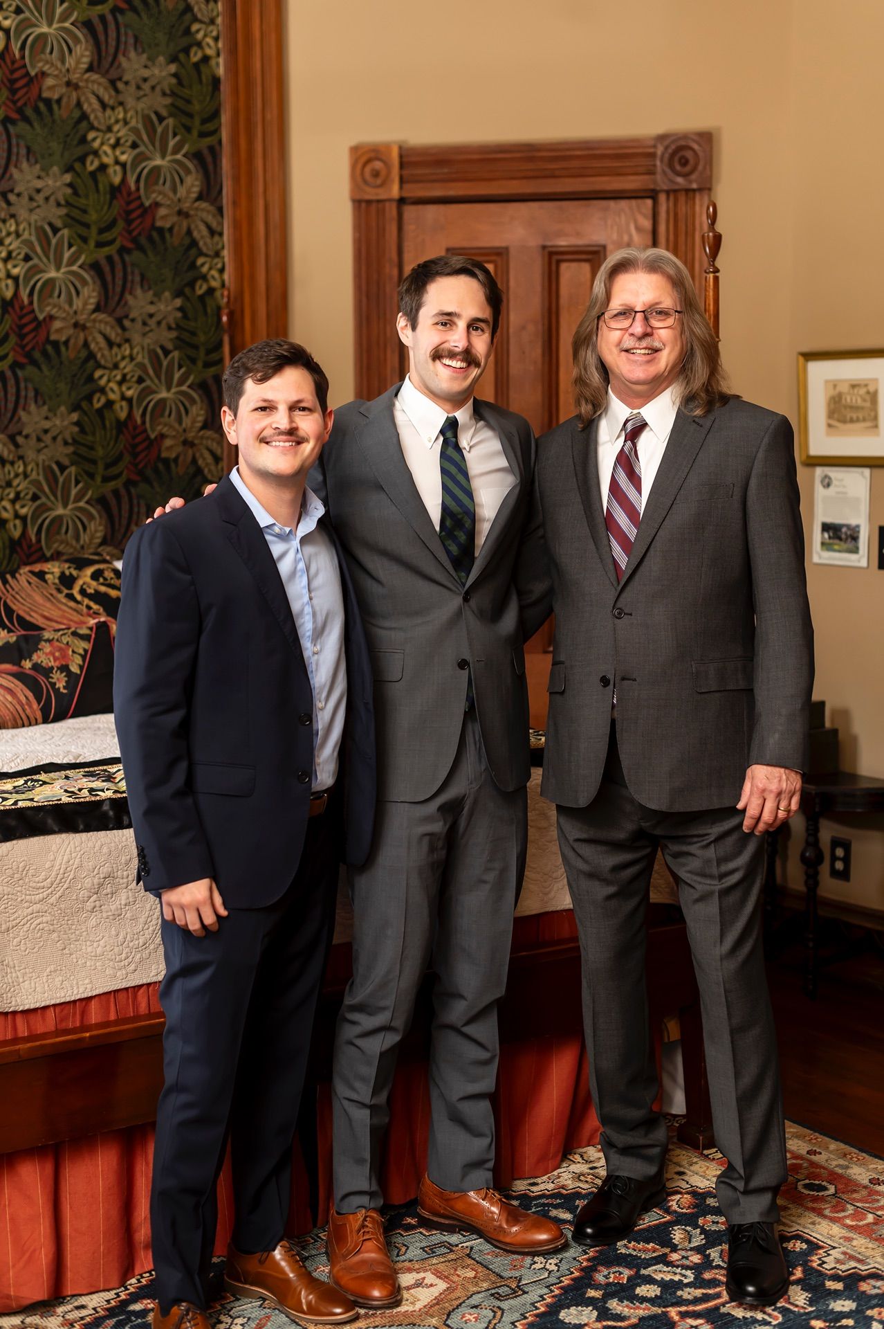Group portrait of people in business suits standing together in a room with patterned carpet.