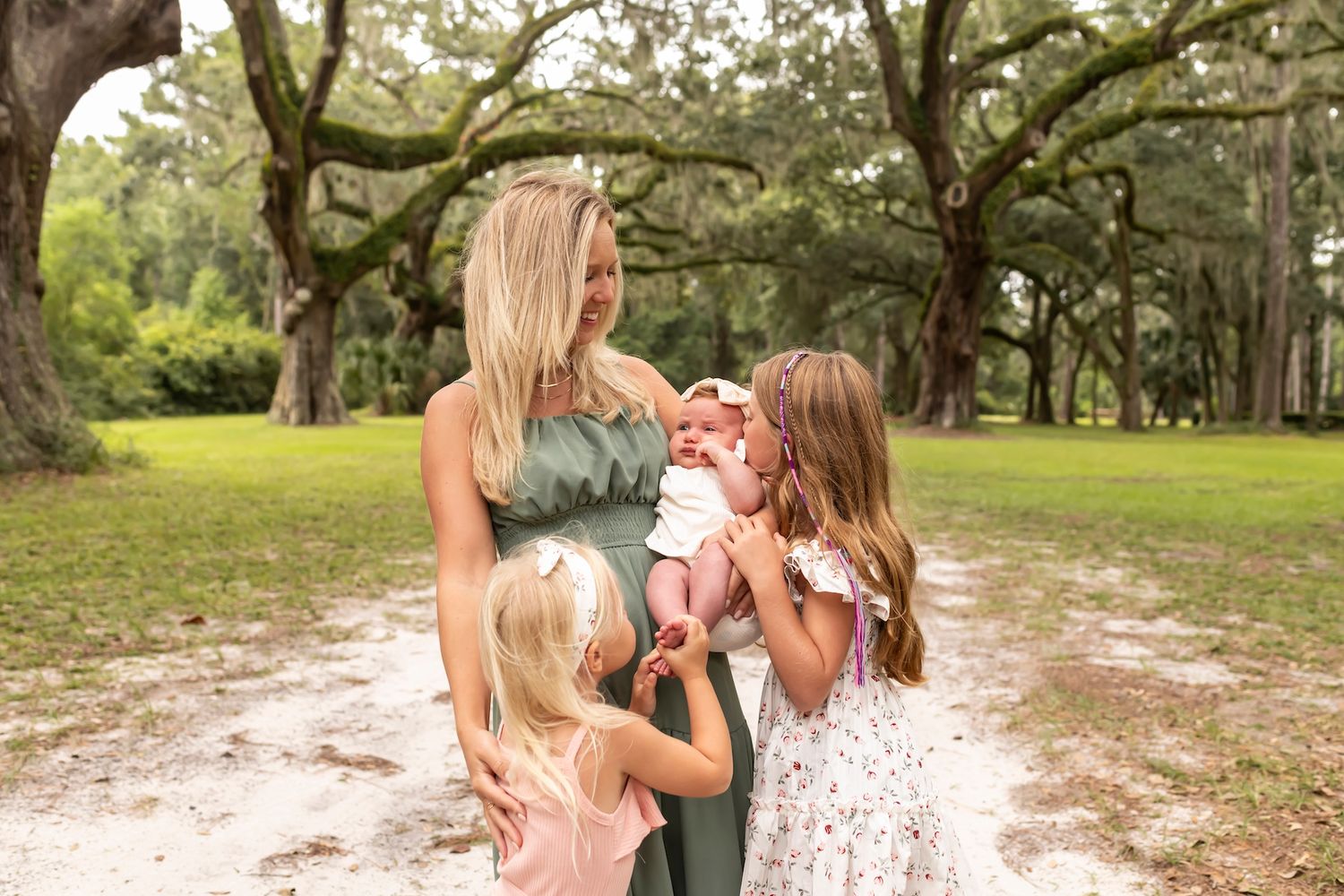 People share a joyful moment together on a sandy path beneath sprawling oak trees in a serene park setting.