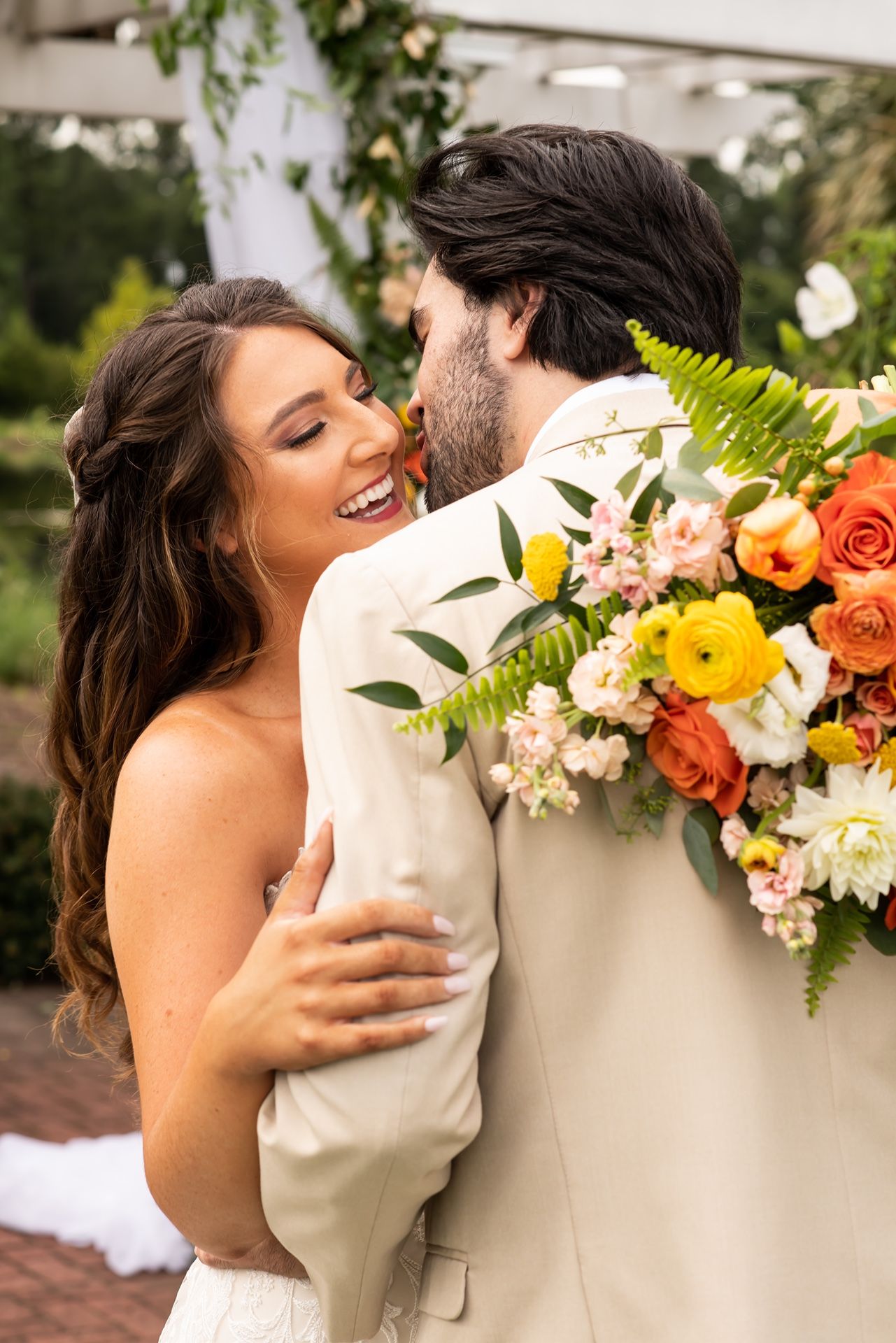 A romantic outdoor wedding moment captured with vibrant orange and yellow floral arrangements.