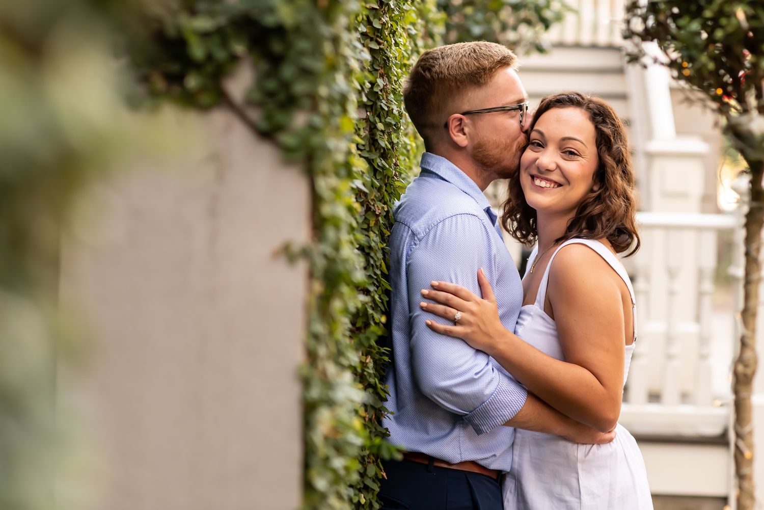 Couple shares tender moment in an ivy-covered garden during engagement photoshoot.